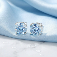 Round cut simulated aquamarine stud earrings in sterling silver on light blue silk with water droplets.