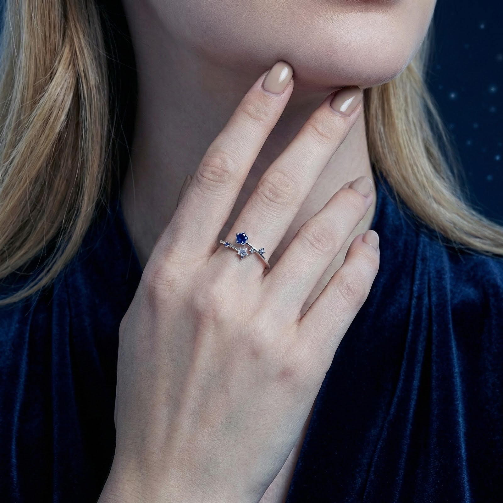 Close-up of the star-themed sterling silver bypass ring with blue sapphires on a model's hand.