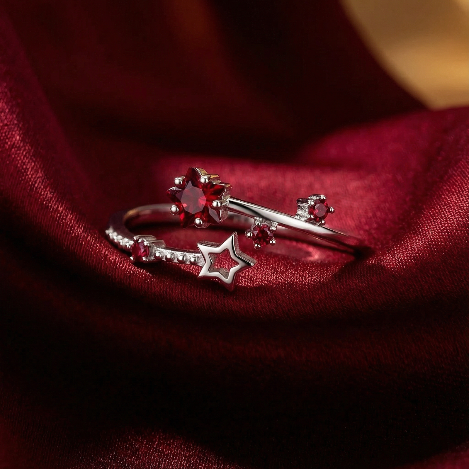 Lyriana star bypass ring in sterling silver with star-cut simulated ruby on red silk fabric.