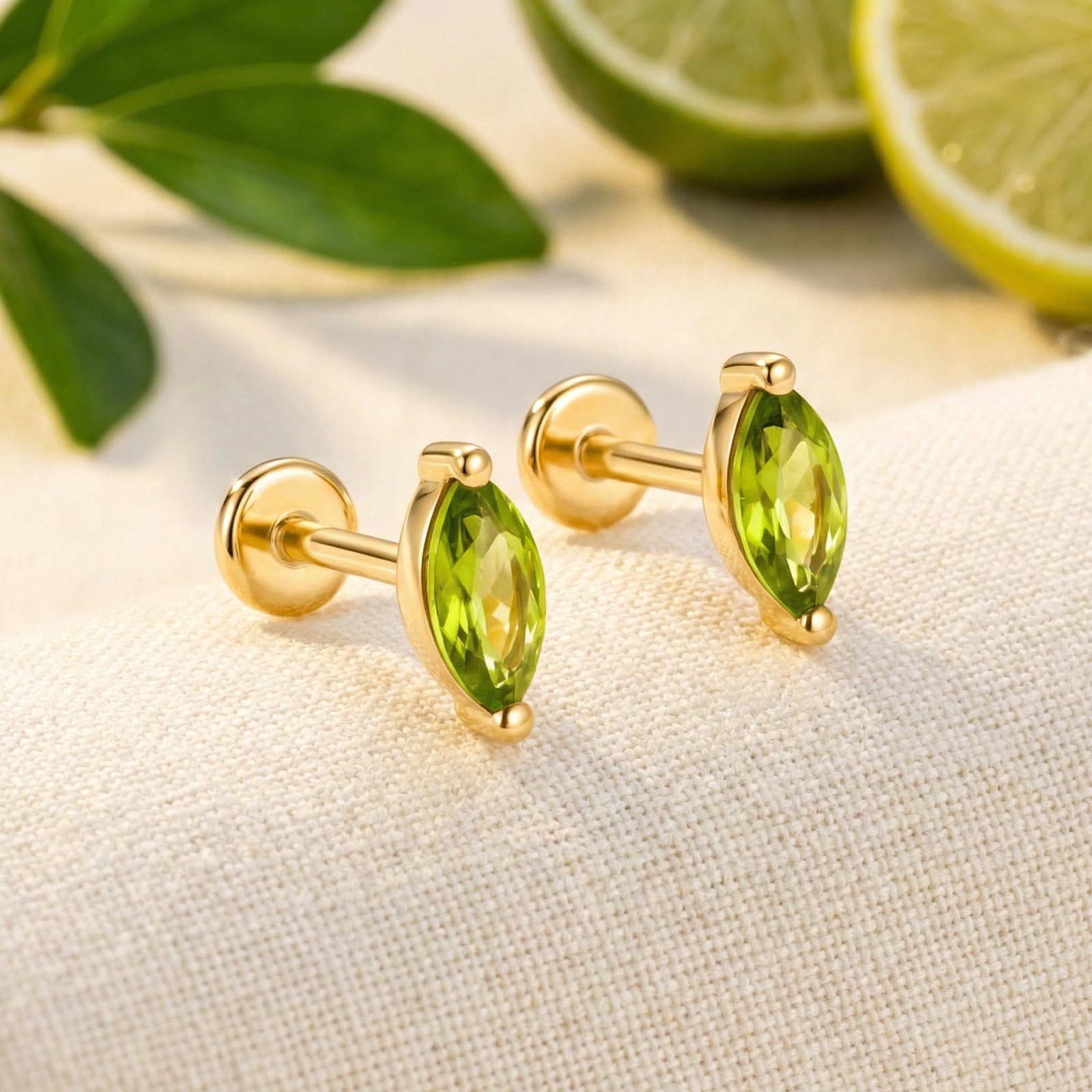 Marquise-cut simulated peridot earrings with flat backs in 18K gold vermeil on white fabric with limes.