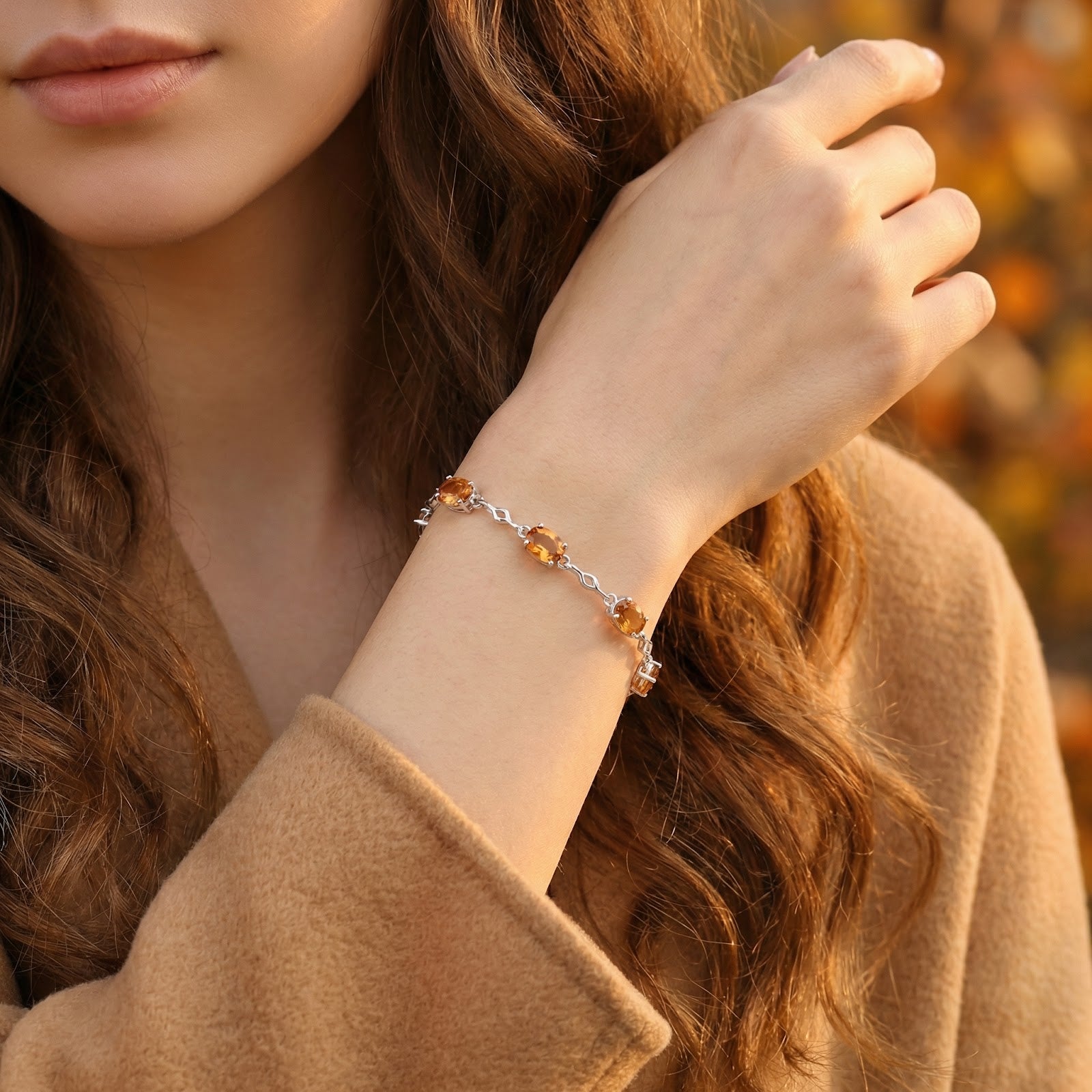 Sterling silver bracelet with orange simulated topaz stones worn on a woman's wrist over a tan coat.