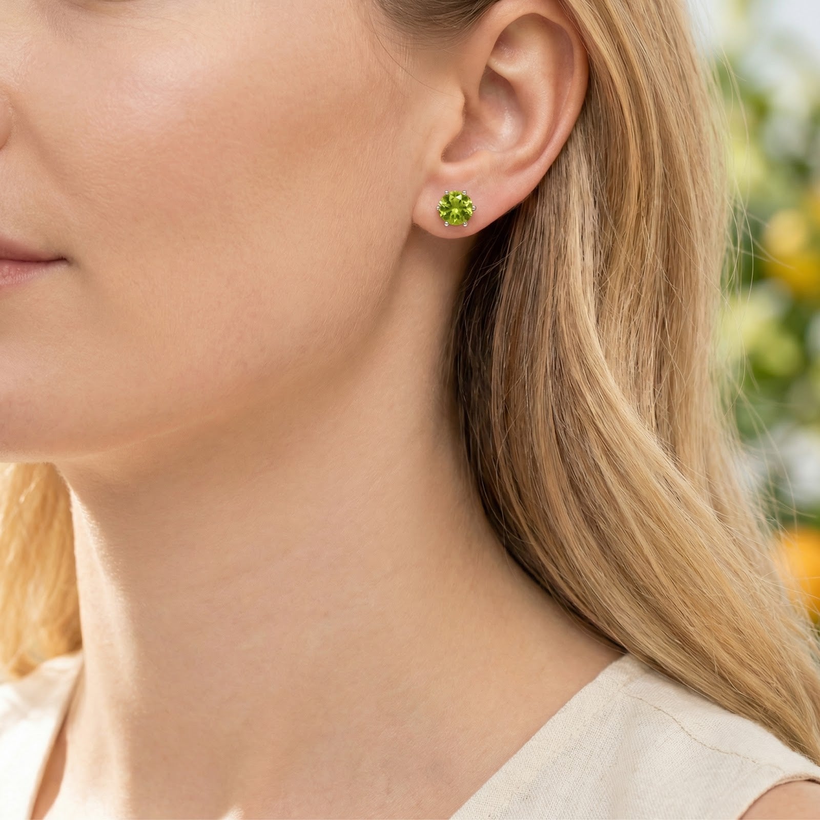 Side profile of a model wearing a round-cut simulated peridot earring in a 925 sterling silver setting.