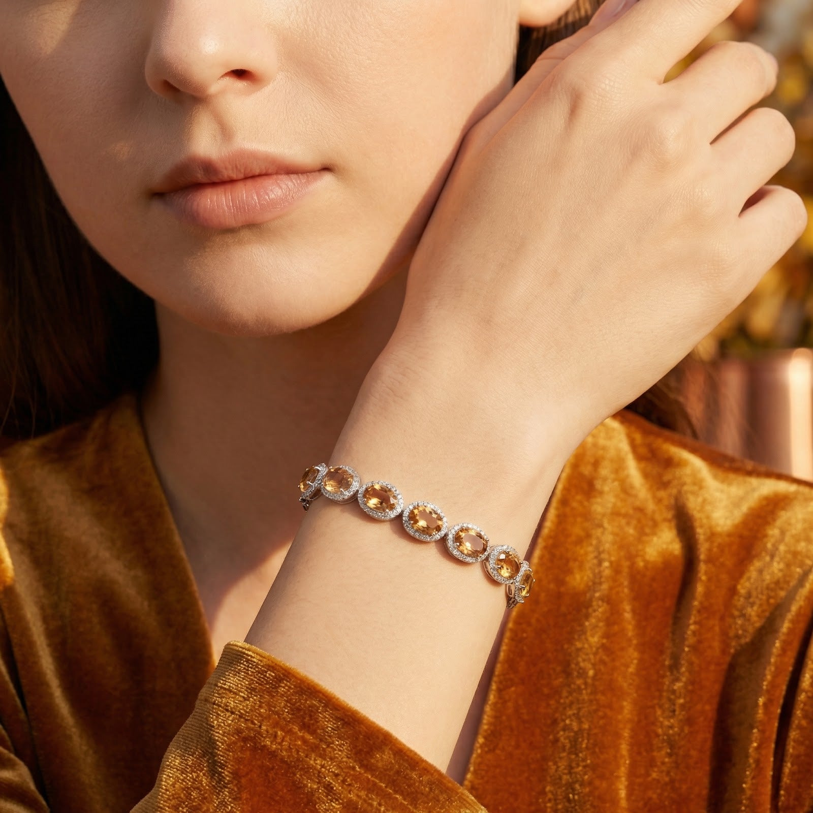 Woman wearing the Alizae sterling silver halo bracelet with honeyed simulated topaz stones on her wrist.
