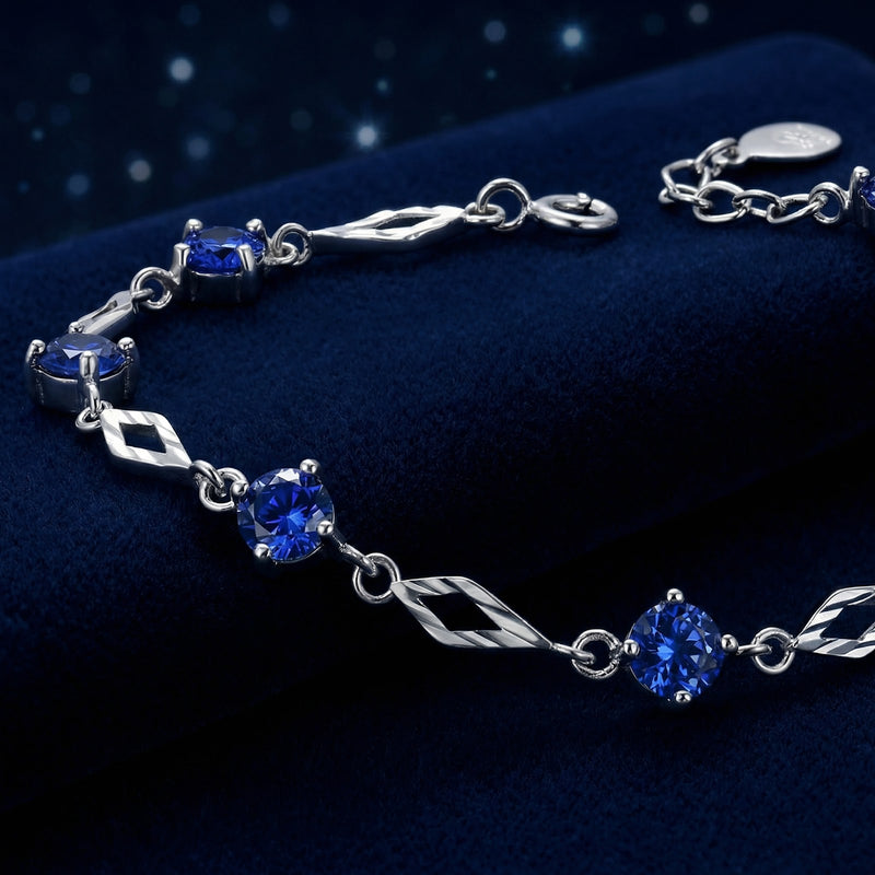 Macro view of round-cut blue sapphires and diamond-shaped silver links on the Nerienne station bracelet.