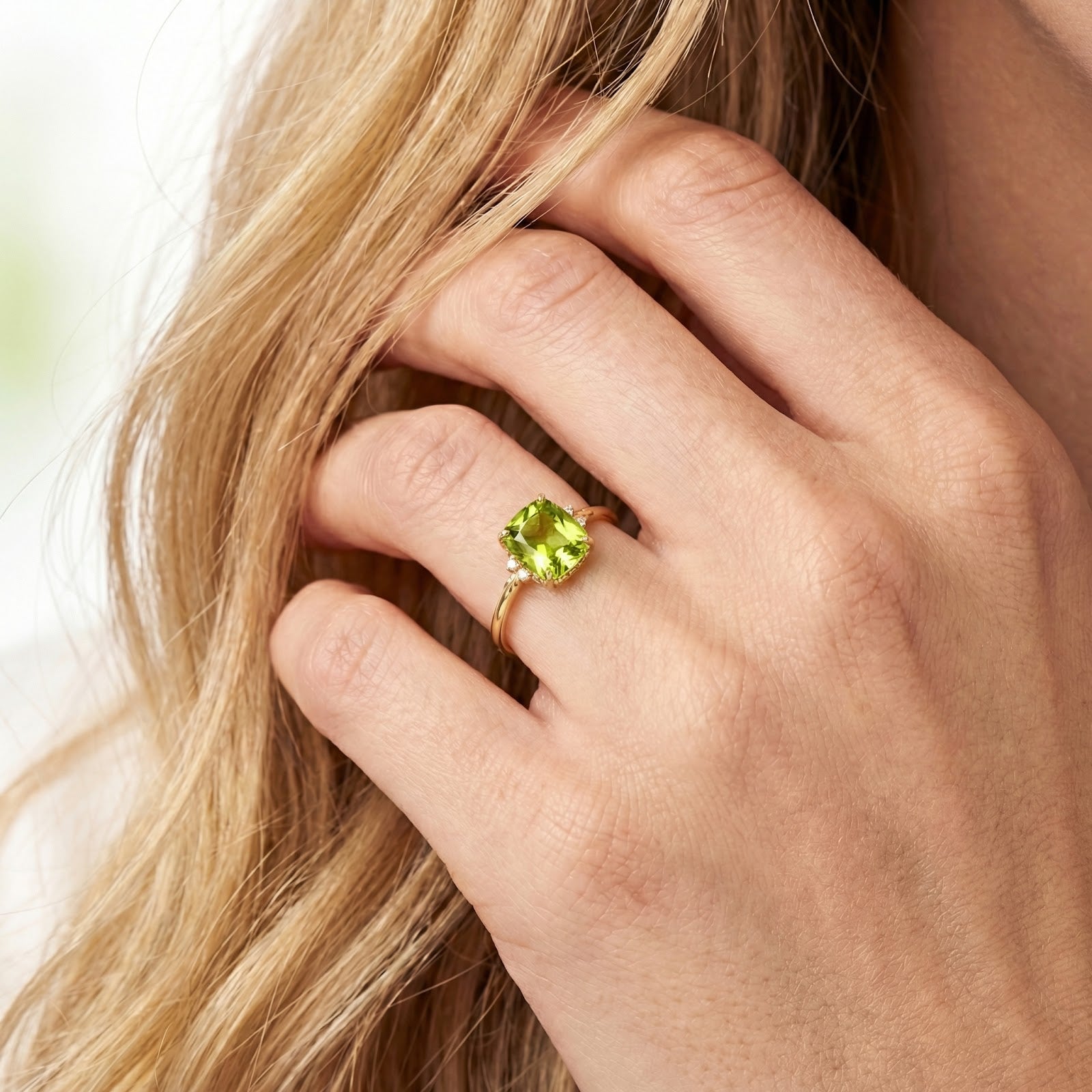 Azurina cushion cut peridot ring in 18K gold vermeil worn on a model's hand while touching her hair.