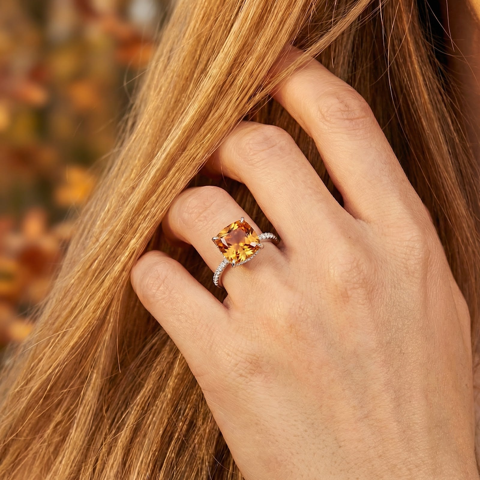 Cushion cut simulated topaz ring in S925 sterling silver worn on a hand touching blonde hair.