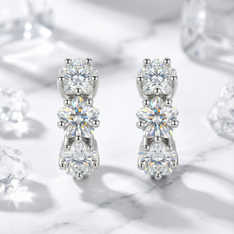 Front view of S925 sterling silver huggie earrings featuring three round-cut simulated diamonds on marble.