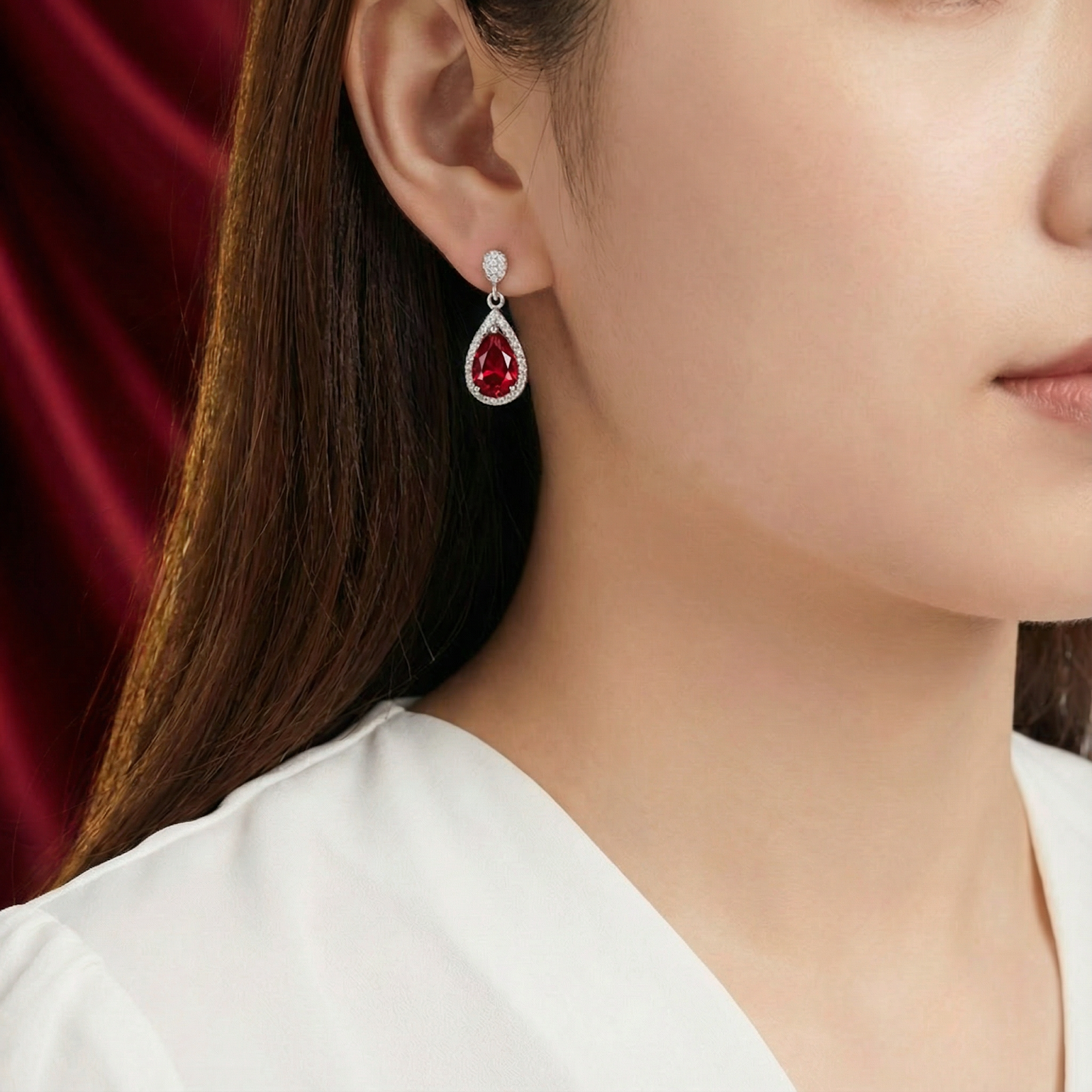 Woman wearing a teardrop S925 sterling silver earring with a deep red simulated ruby.