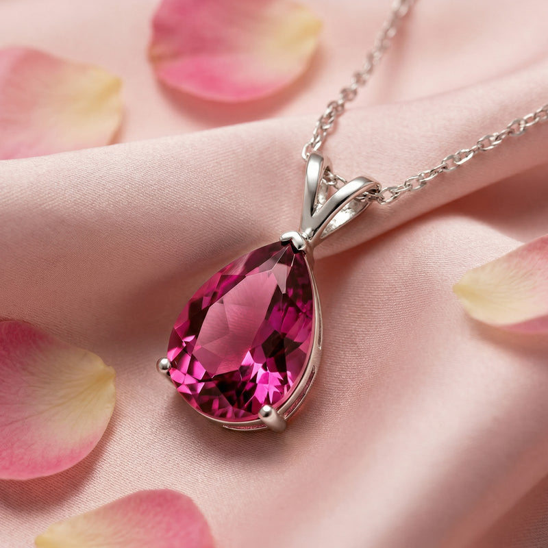 Close-up of a pear-cut simulated pink tourmaline pendant set in sterling silver on pink fabric.