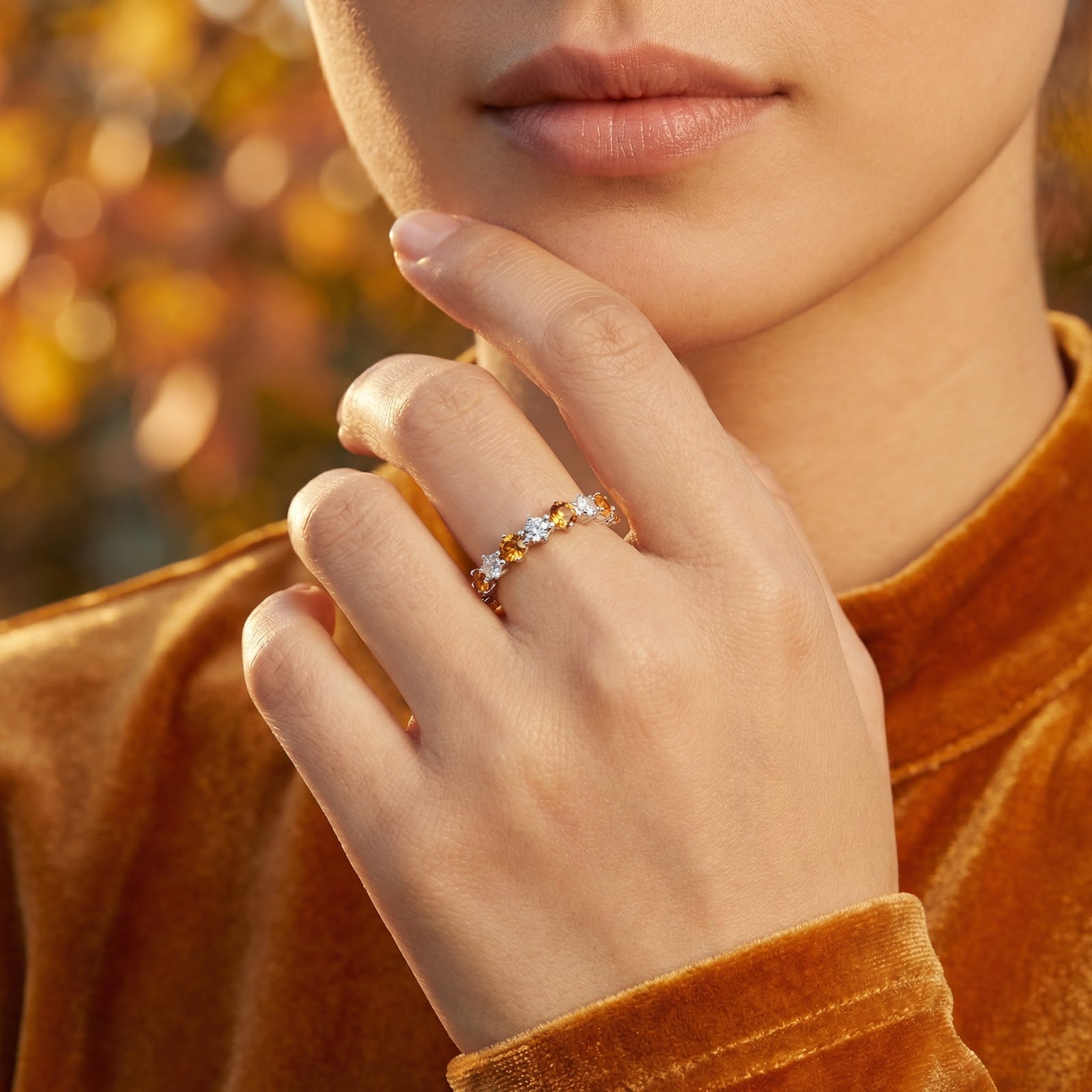 Close-up of the Novara sterling silver ring with honey-colored simulated topaz stones on a model's finger.
