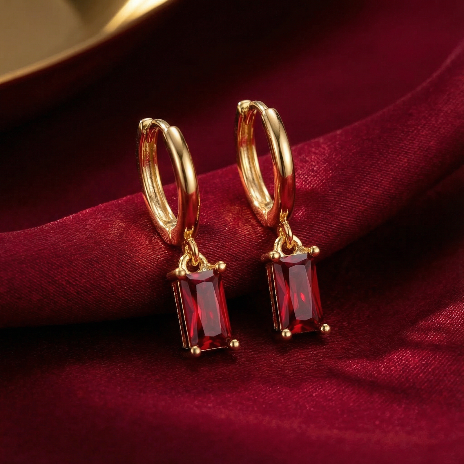 Close-up of 18K gold vermeil earrings showing the faceted emerald-cut simulated ruby stones.