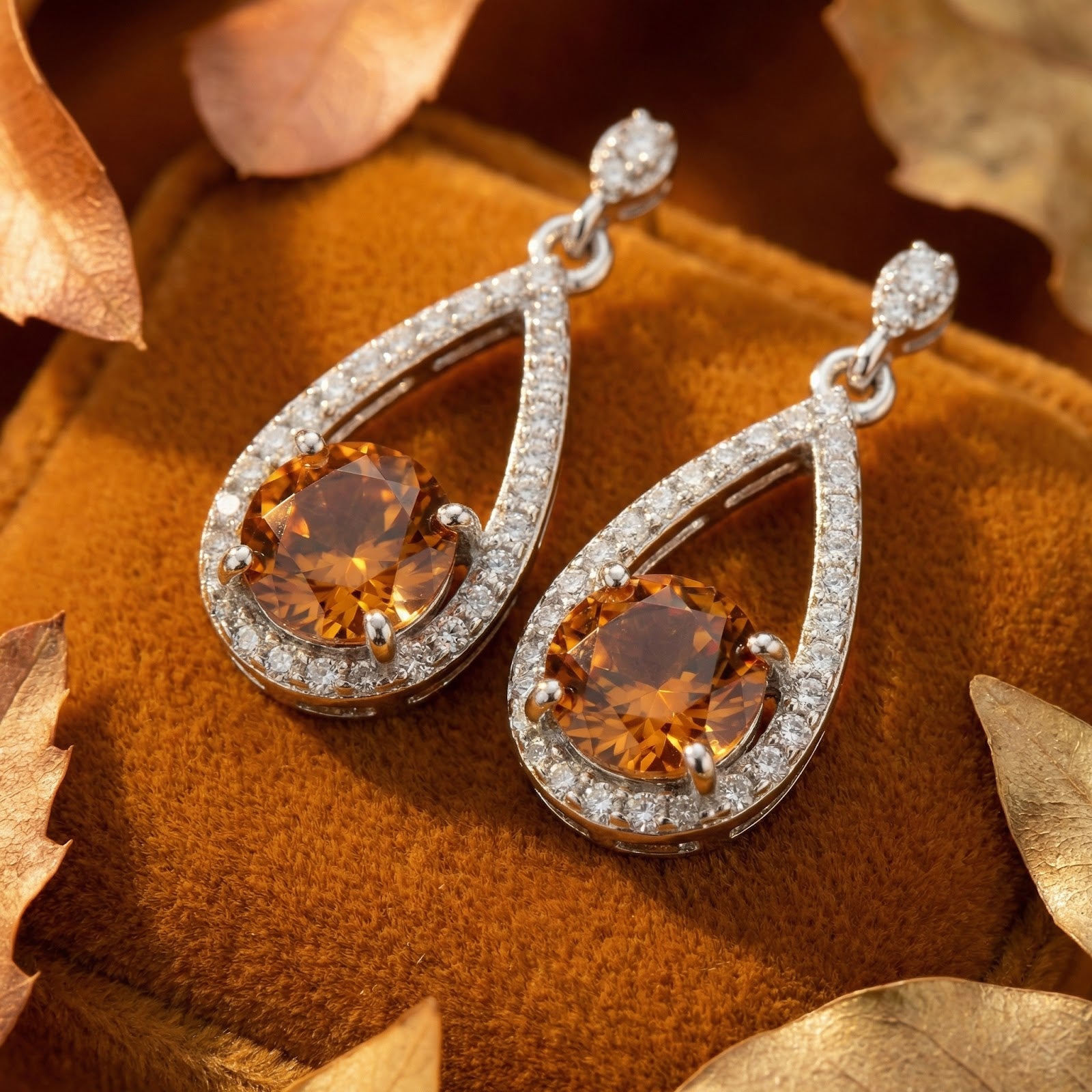 Close-up of S925 sterling silver drop earrings featuring round-cut honeyed simulated topaz and pavé halo.