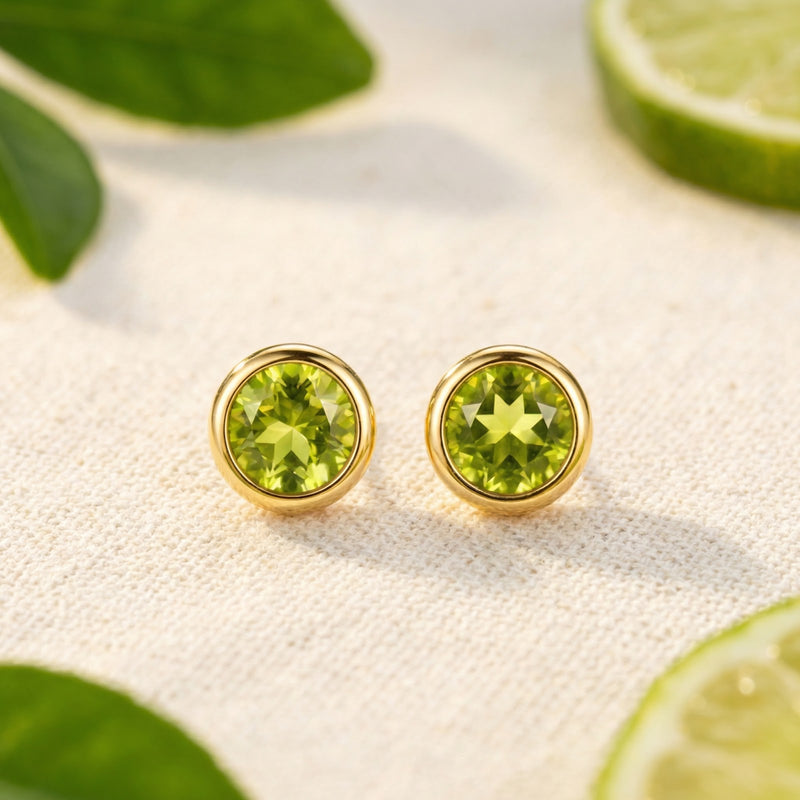 Front view of round-cut simulated peridot stud earrings in 18K gold vermeil bezel settings on a neutral surface.
