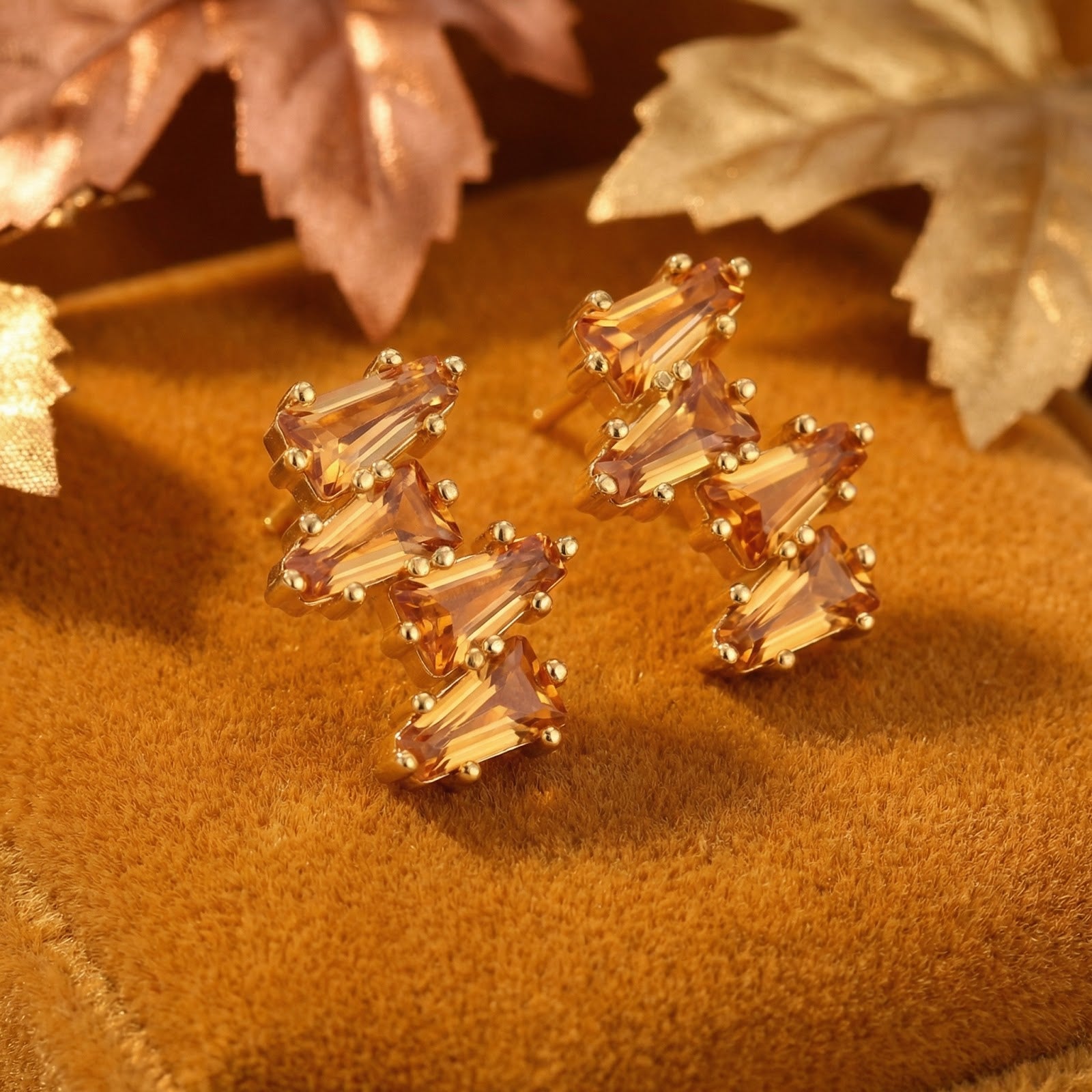 18K gold vermeil cluster earrings with tapered baguette simulated topaz stones on brown velvet with autumn leaves.
