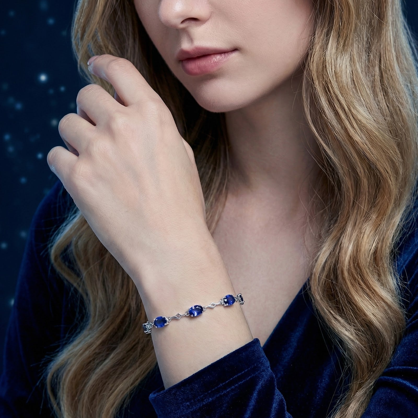 Woman wearing the S925 sterling silver station bracelet with blue simulated sapphires on her wrist.