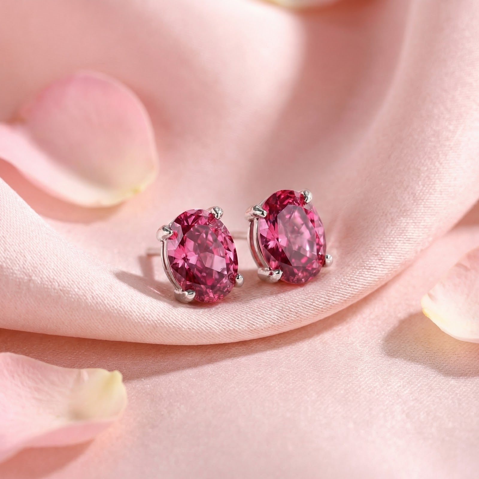 Oval cut simulated pink tourmaline stud earrings in sterling silver on pink satin with rose petals.