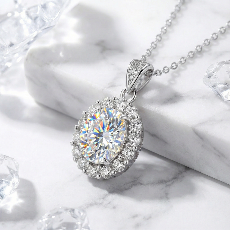 Angled view of the Elianthe oval halo simulated diamond pendant in silver on a marble background.