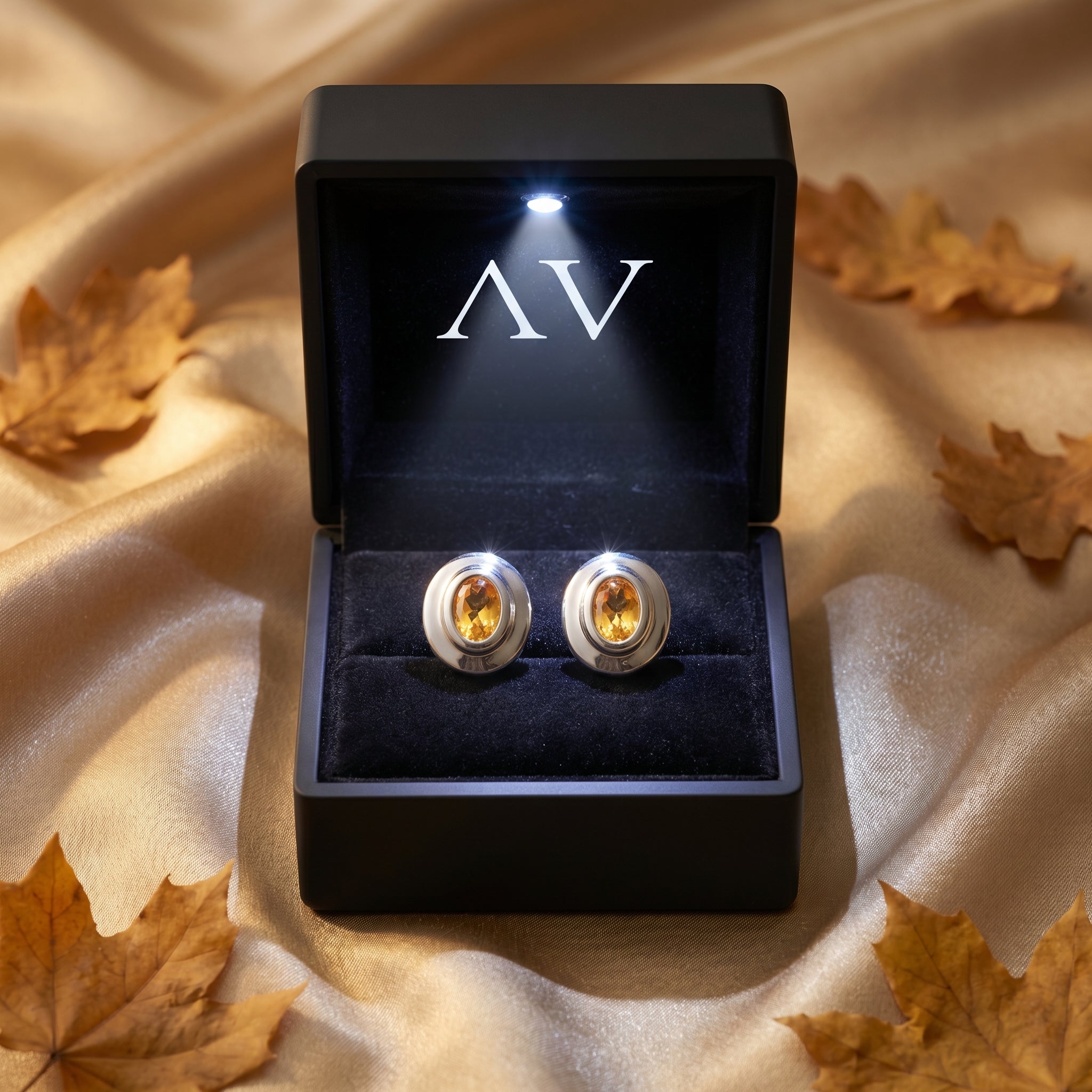 Silver oval cut citrine earrings presented in a black lighted gift box with autumn leaves.