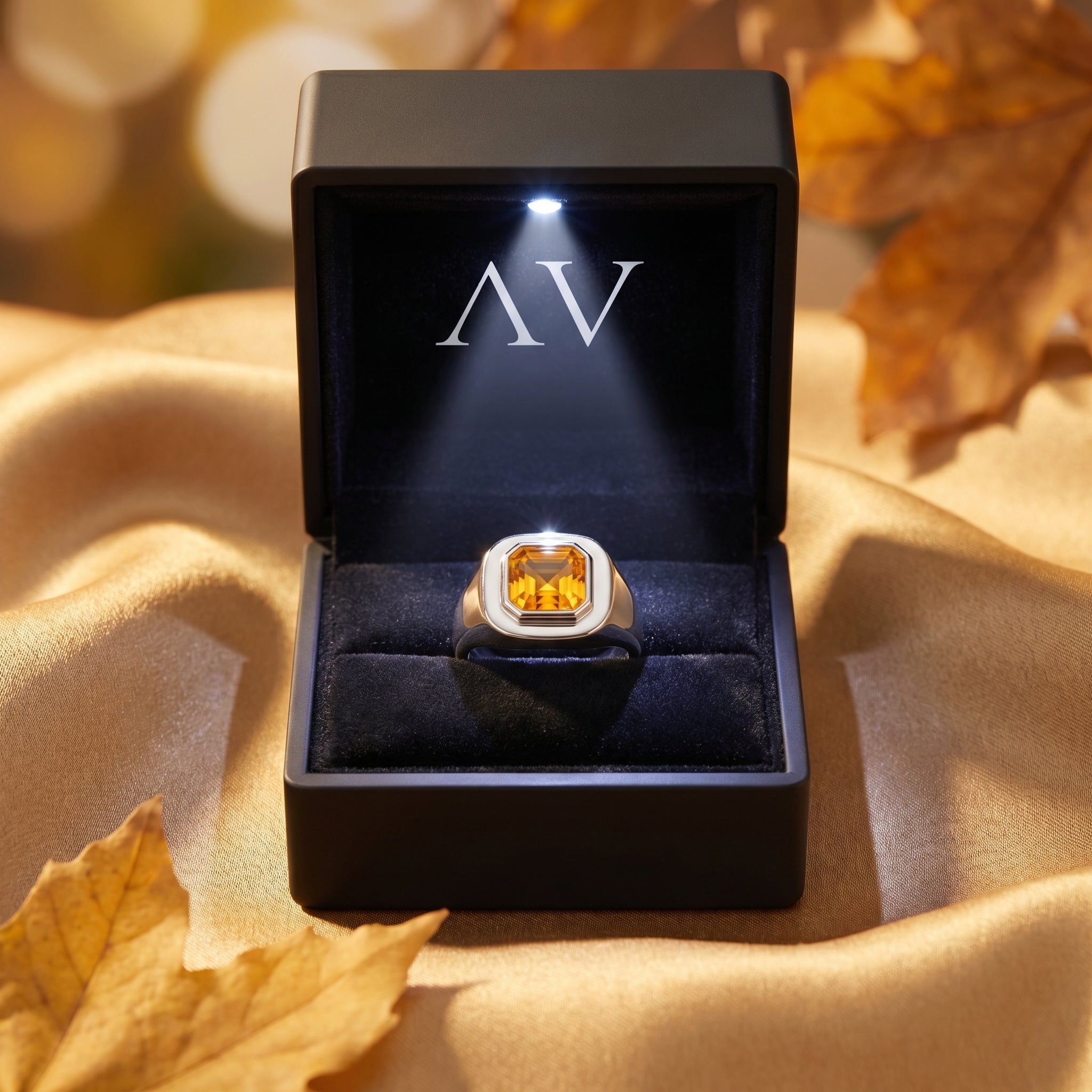 Silver natural citrine Asscher-cut ring inside a black LED-lit presentation box on golden fabric with autumn leaves.