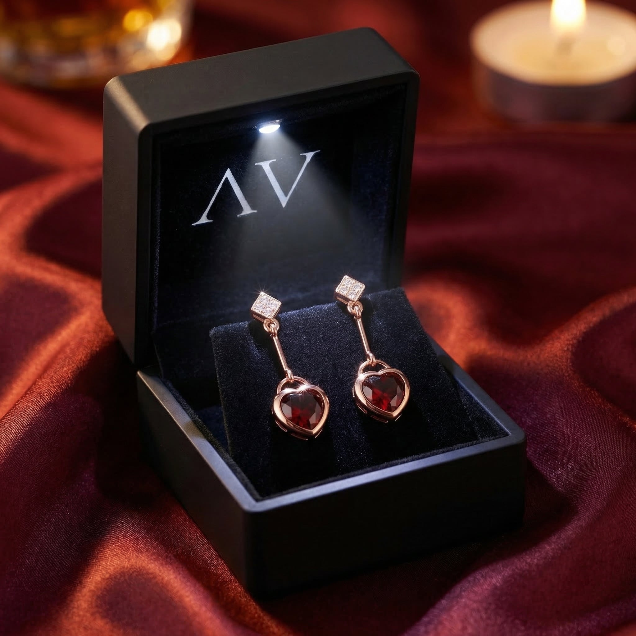 Rosalette 18K rose gold heart-cut garnet drop earrings presented in a lighted black jewelry gift box.
