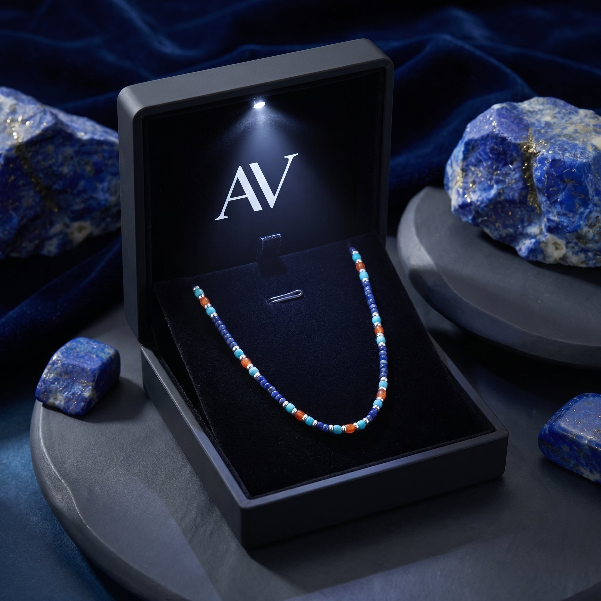 Starfall 5mm beaded lapis necklace in a black LED-lit AV jewelry box surrounded by raw lapis stones.