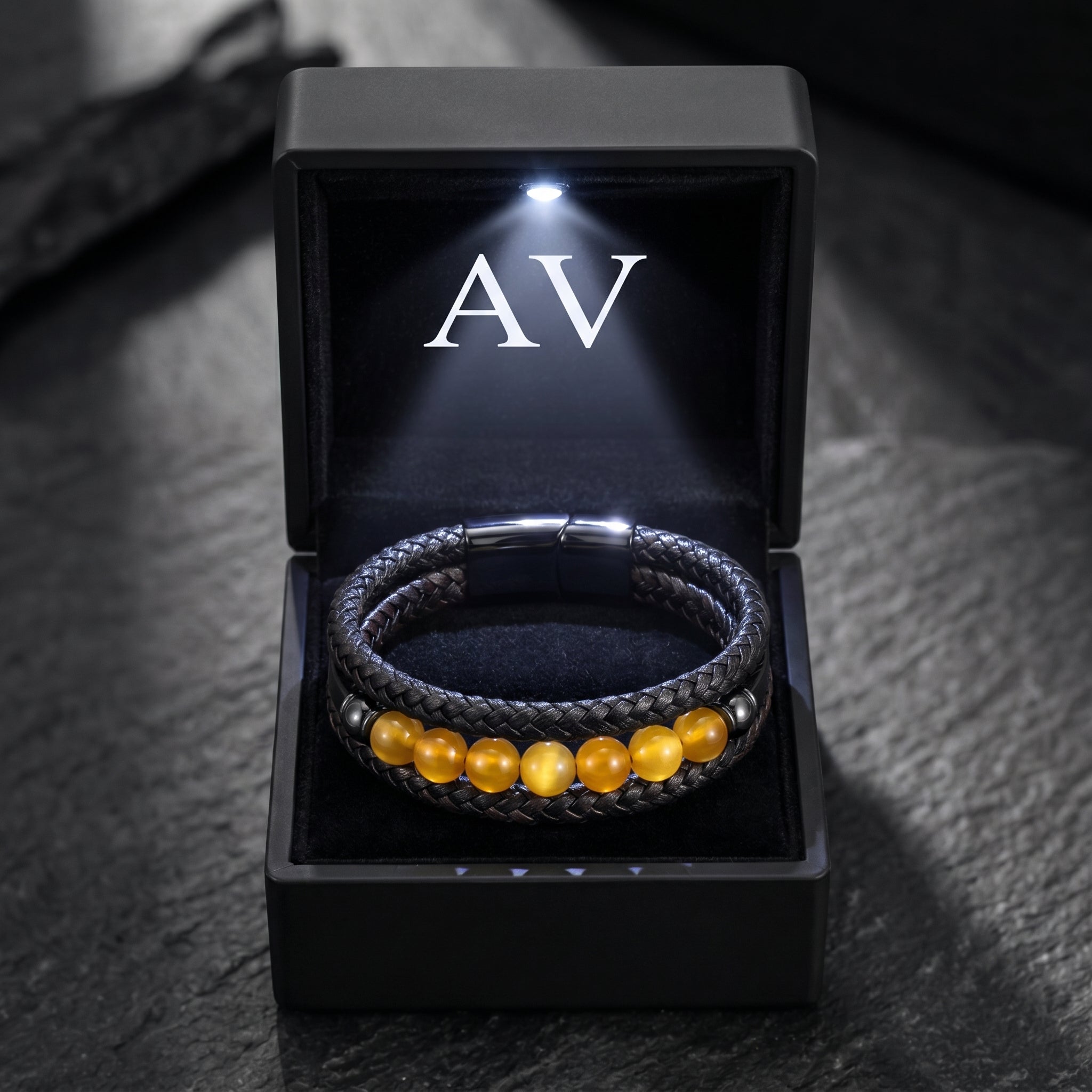 Black stainless steel and leather bracelet with round yellow tiger eye beads inside a lighted black gift box.