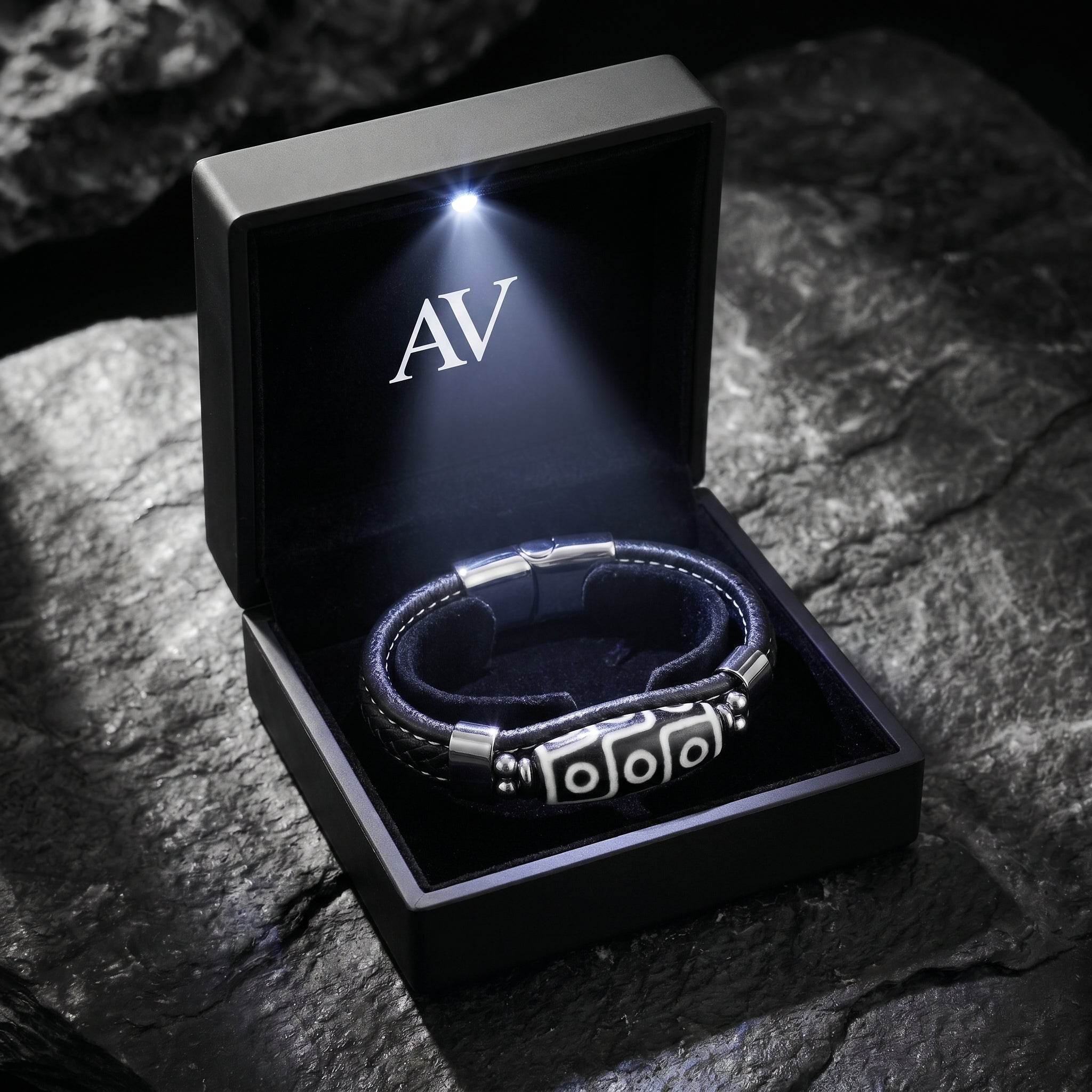 Black leather bracelet with silver-tone 316L stainless steel hardware inside a lighted black AV branded gift box.
