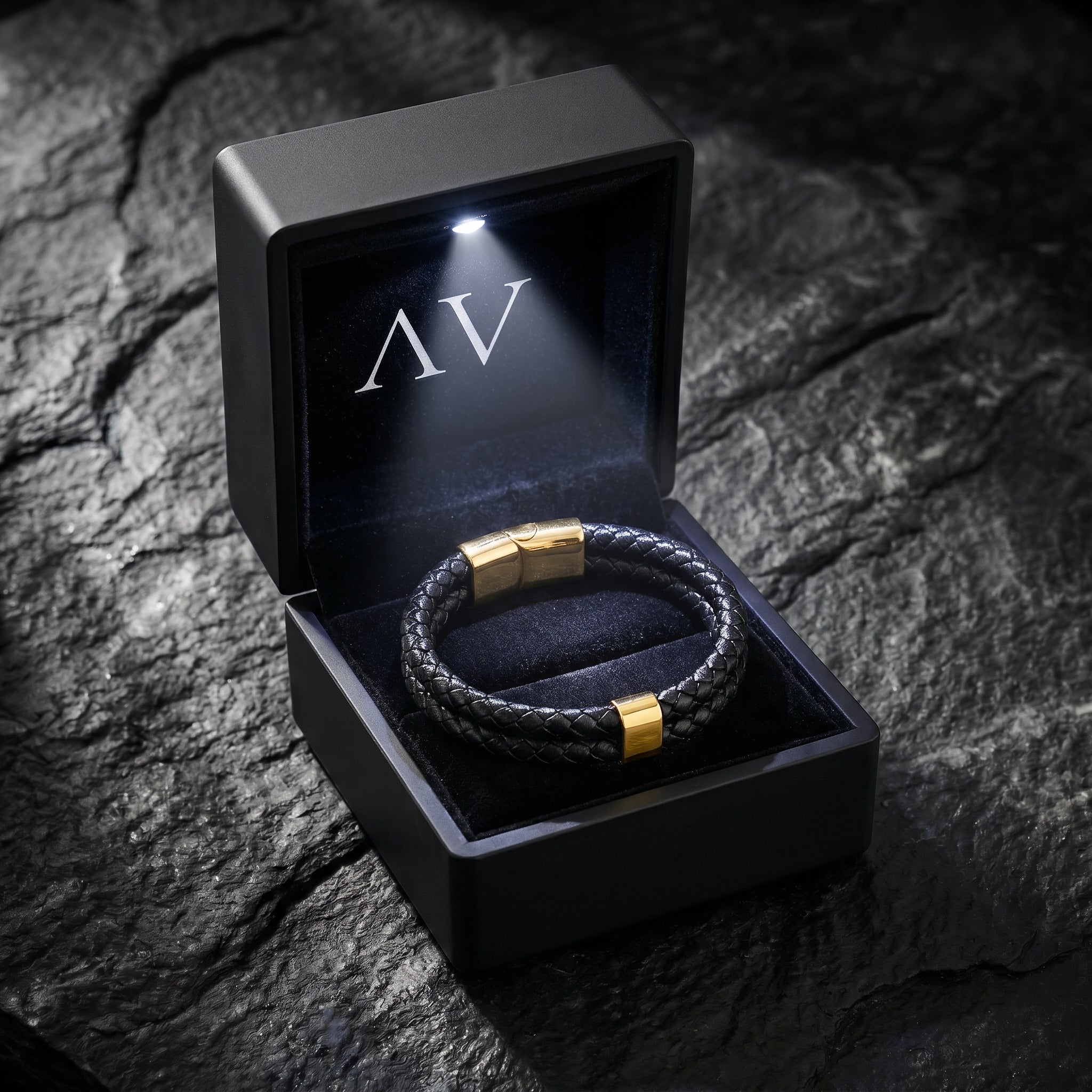 Black braided leather bracelet with gold accents inside a premium black LED-lit jewelry gift box.