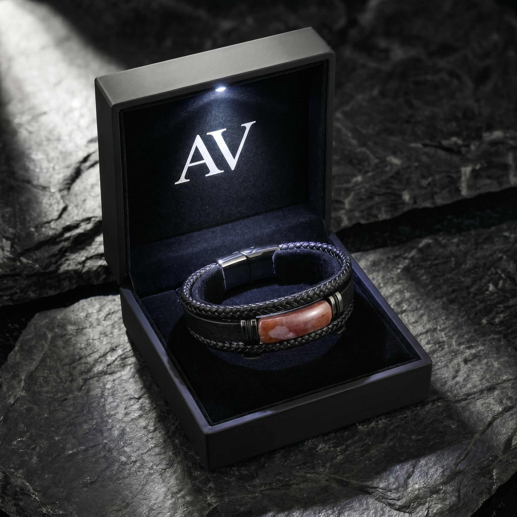 The Apex leather bracelet inside a premium black LED-lit gift box with the AV logo on a dark rock surface.