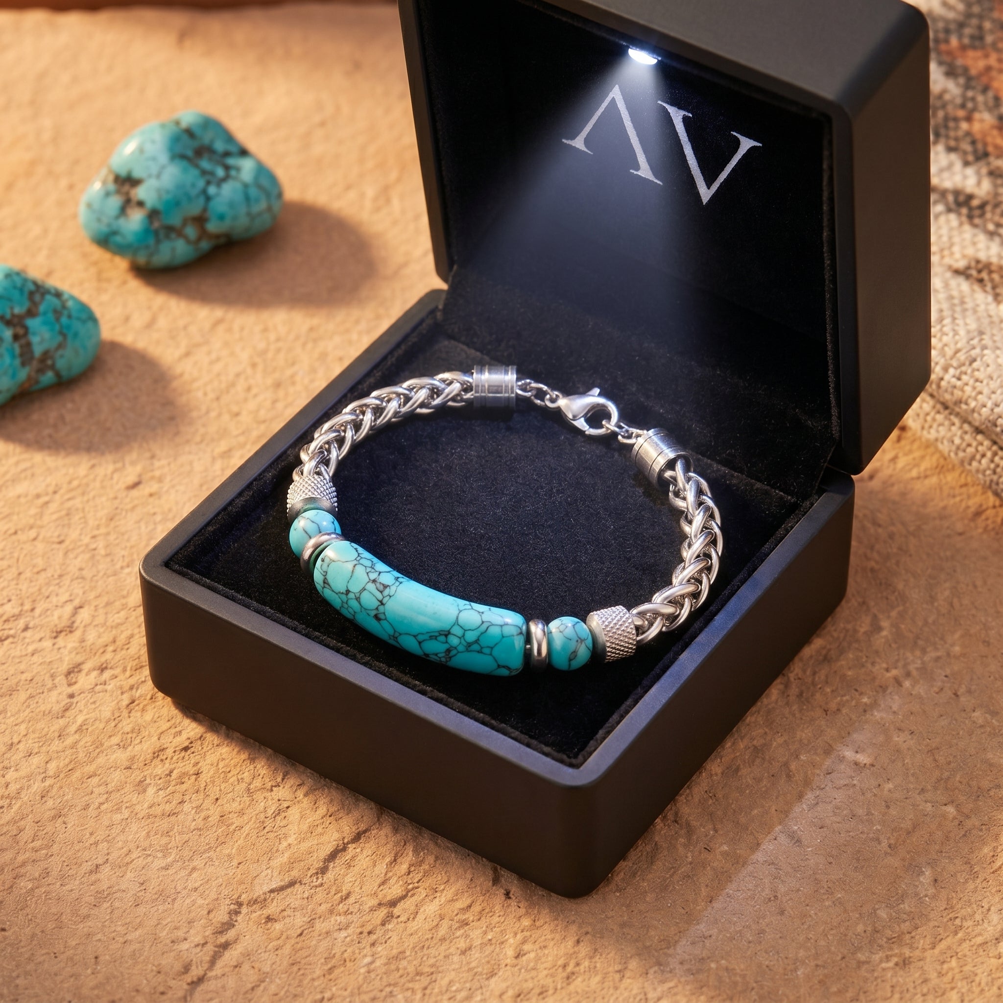 Silver stainless steel turquoise bracelet presented in a premium black lighted gift box on a desert stone background.
