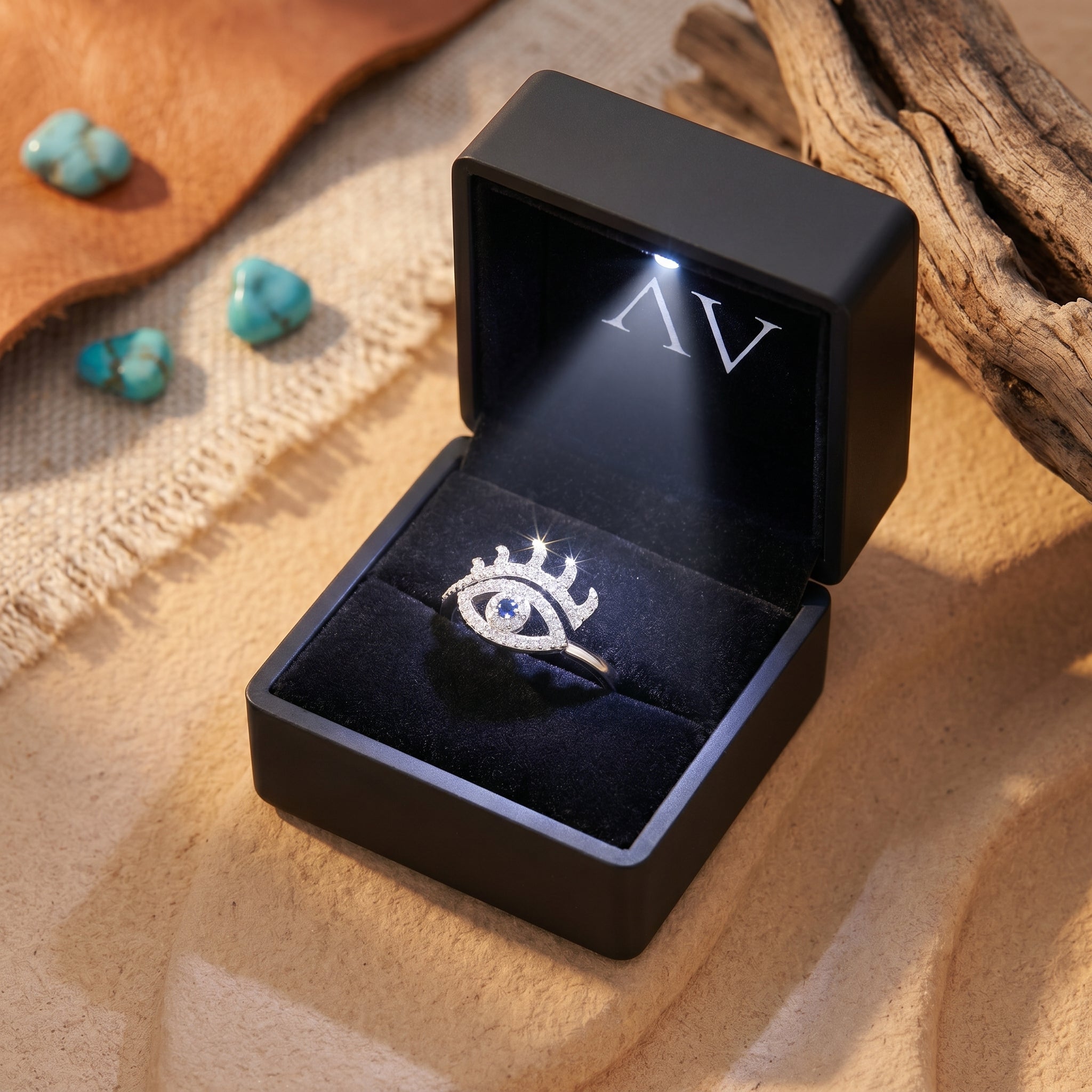 Sterling silver eye-shaped ring with a blue center stone presented in a black LED-lit jewelry gift box.