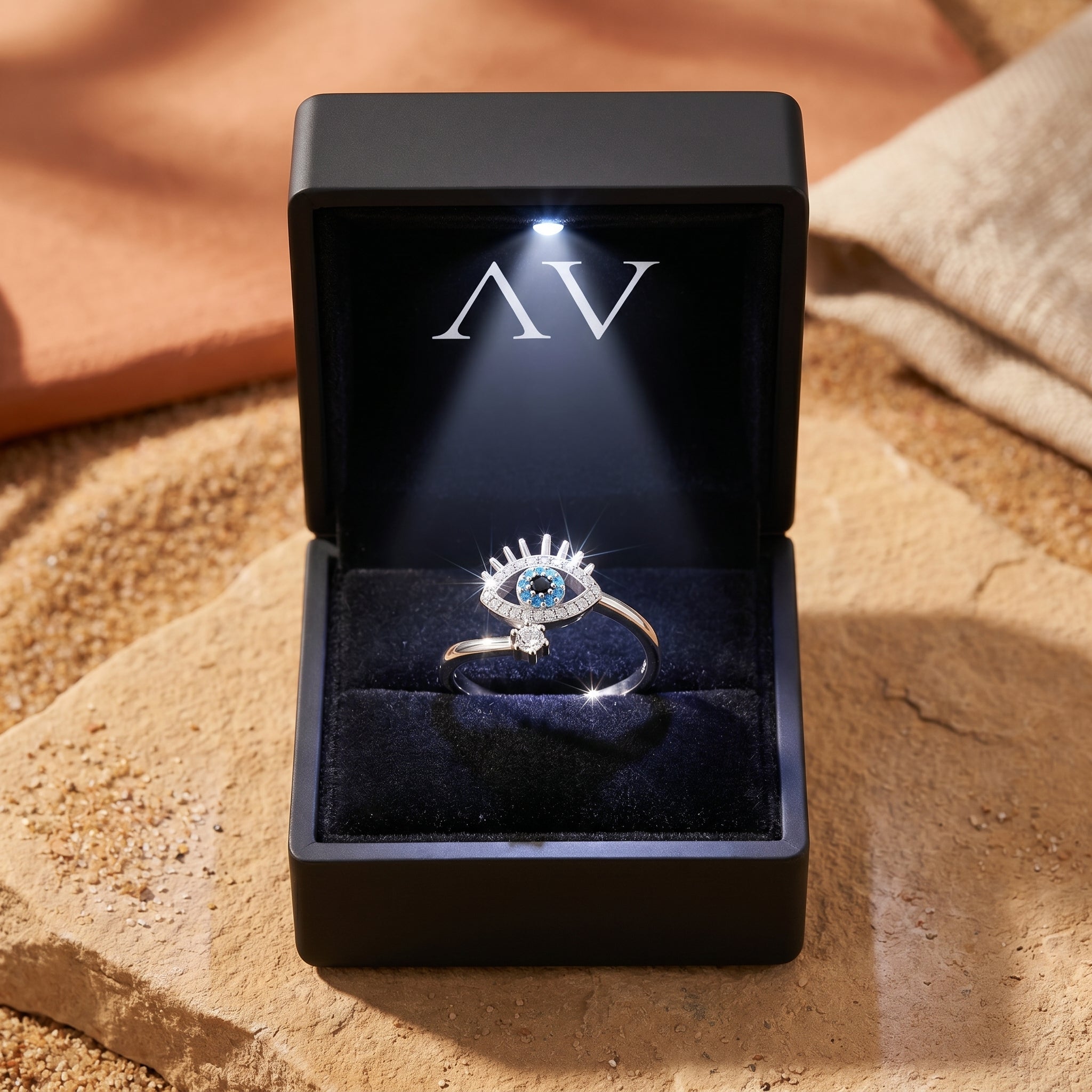 Silver Amaya turquoise evil eye ring inside a premium black LED-lit gift box on a desert landscape.