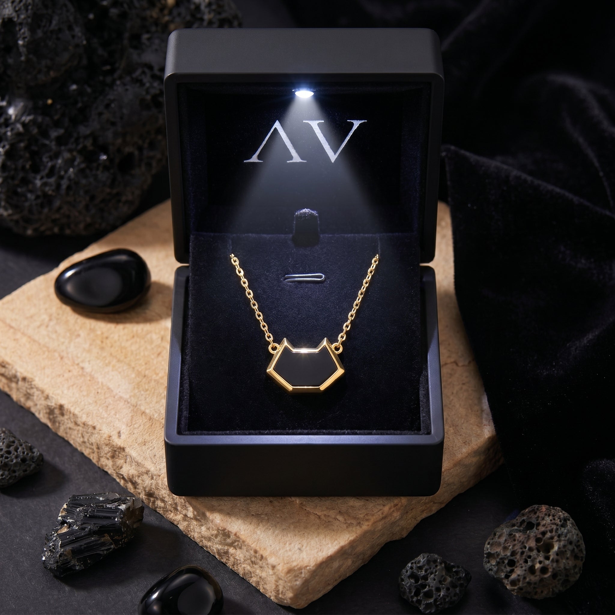 The Umbra Onyx Necklace in 18K gold plating displayed inside a black LED-lighted jewelry box with AV logo.