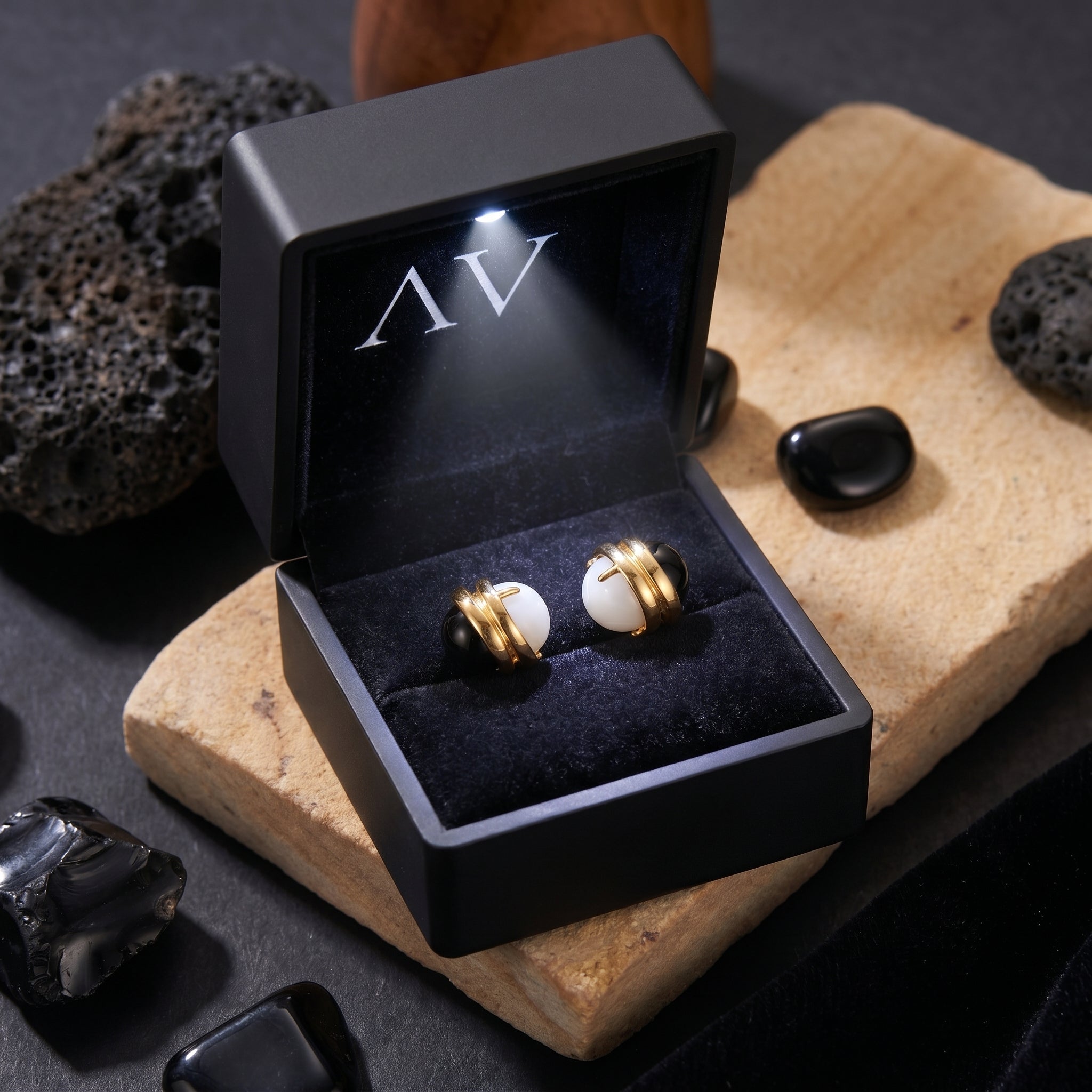 18K gold plated Ravenna onyx and chalcedony earrings inside a black LED-lit jewelry gift box on a stone slab.