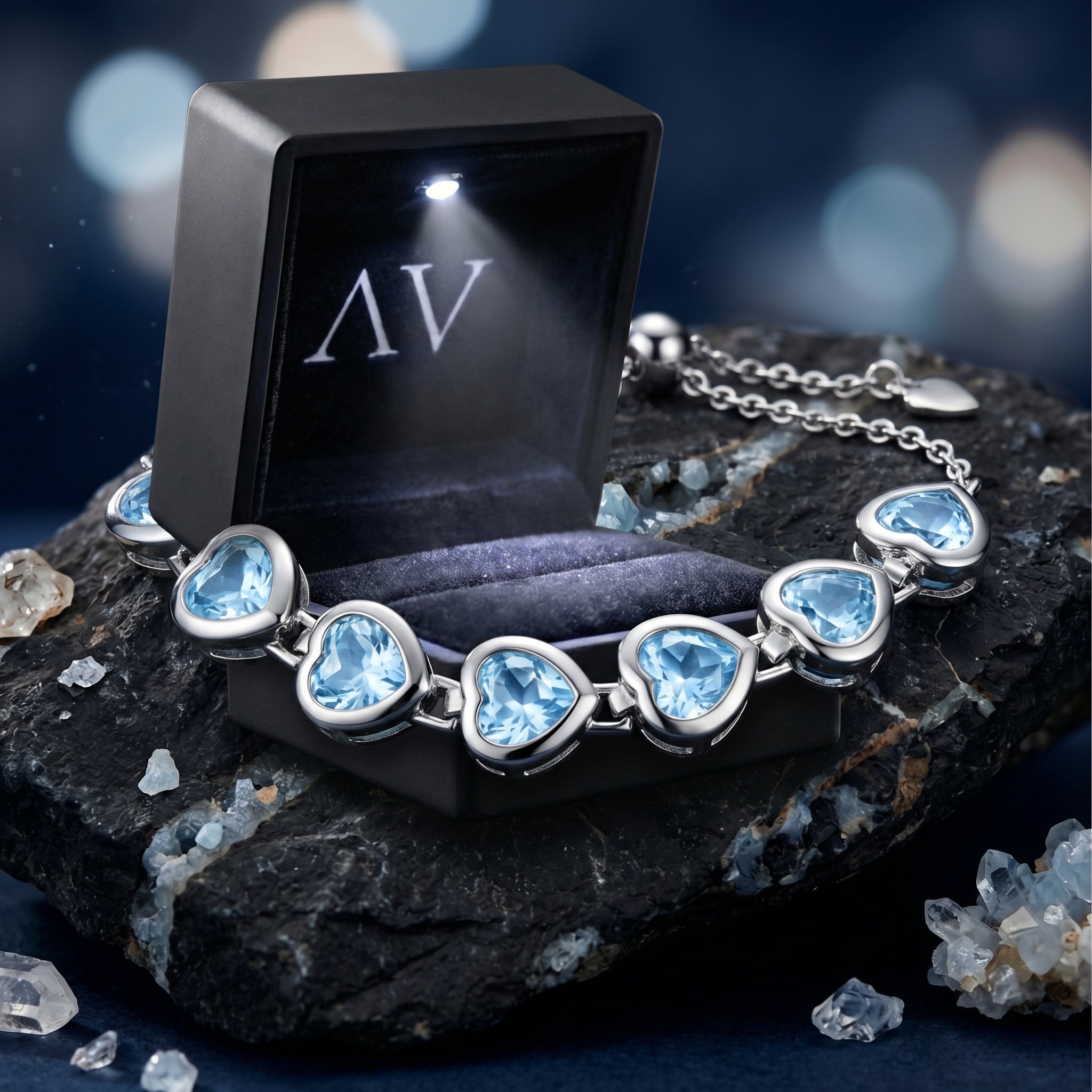 Silver heart-cut blue topaz bracelet shown with an open illuminated black AV branded jewelry gift box.