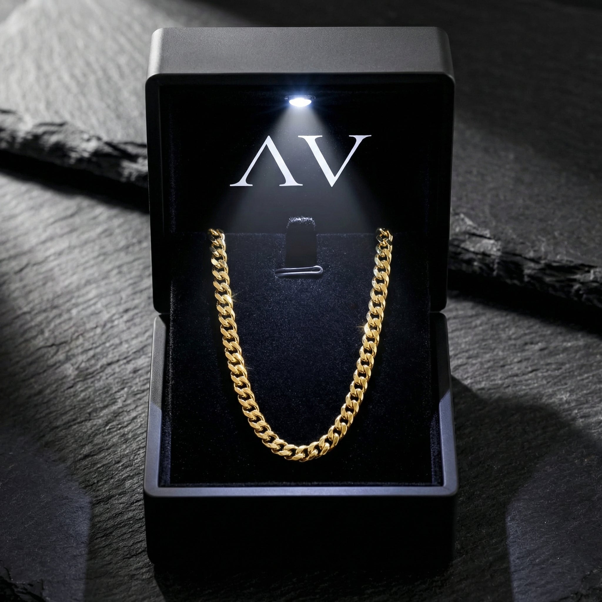 Gold Connell curb chain presented in a premium black LED-lit jewelry gift box on a stone surface.
