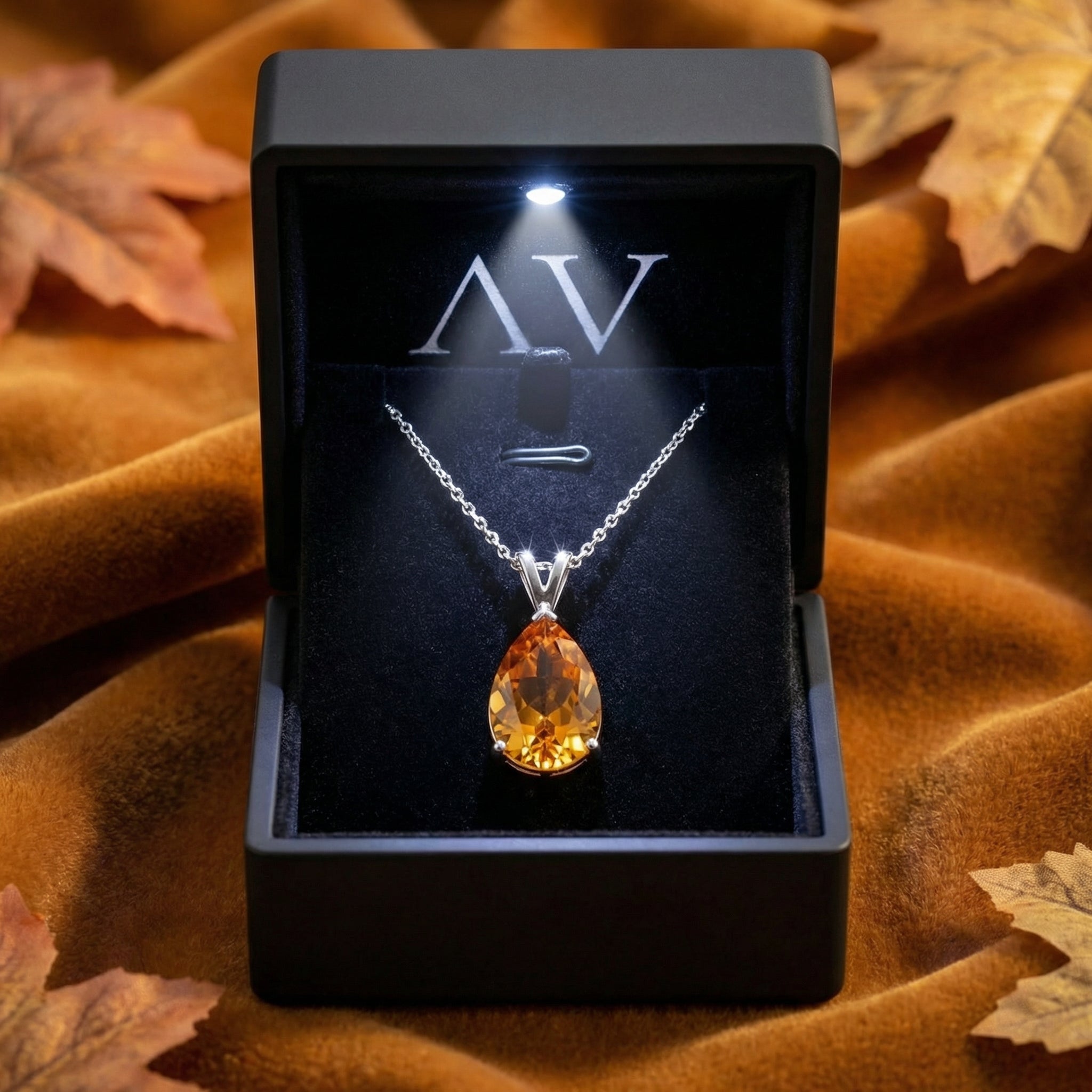 Sterling silver pear-cut honey moissanite necklace presented in a lighted black jewelry gift box.
