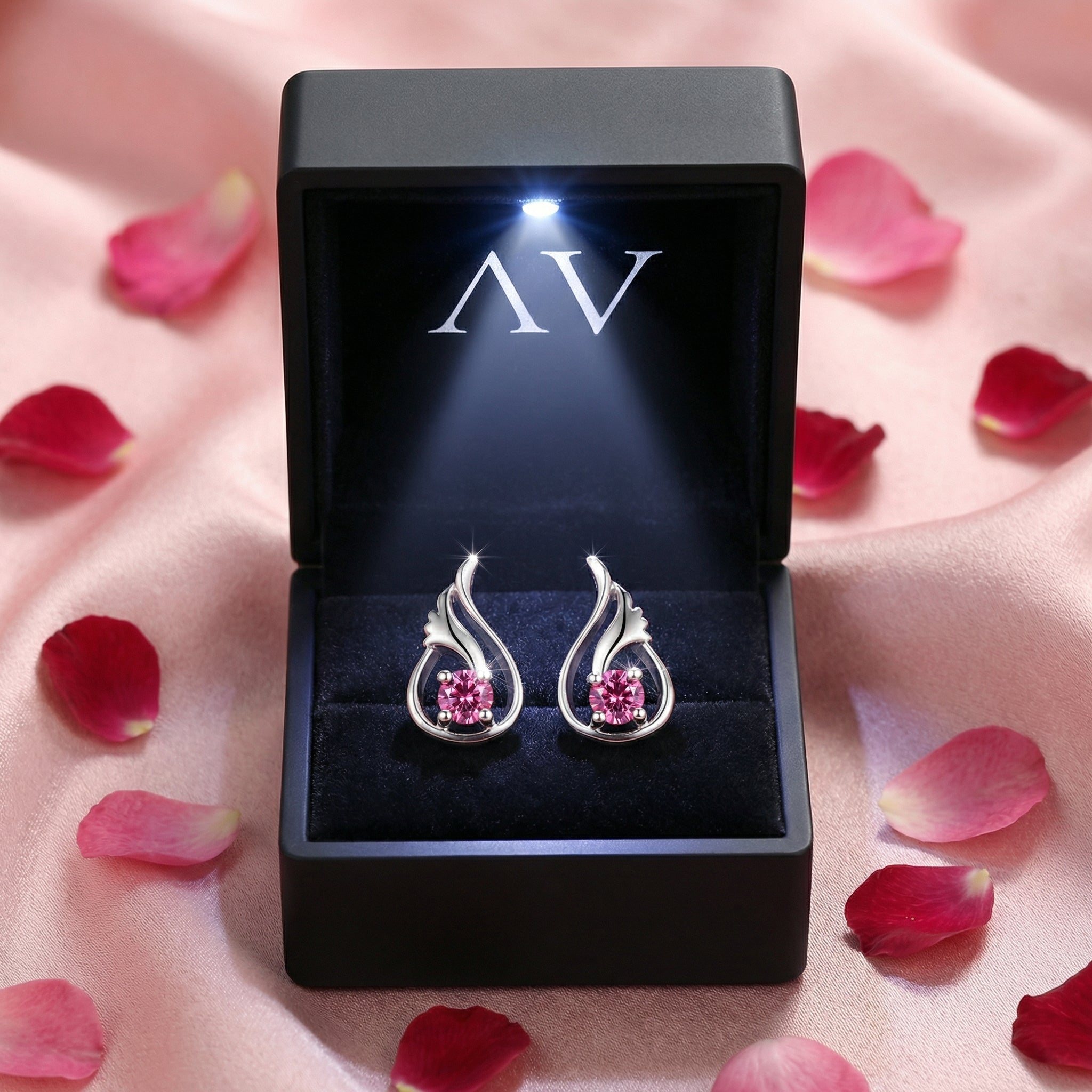 Sterling silver simulated pink tourmaline earrings in a black LED-lighted gift box with rose petals.