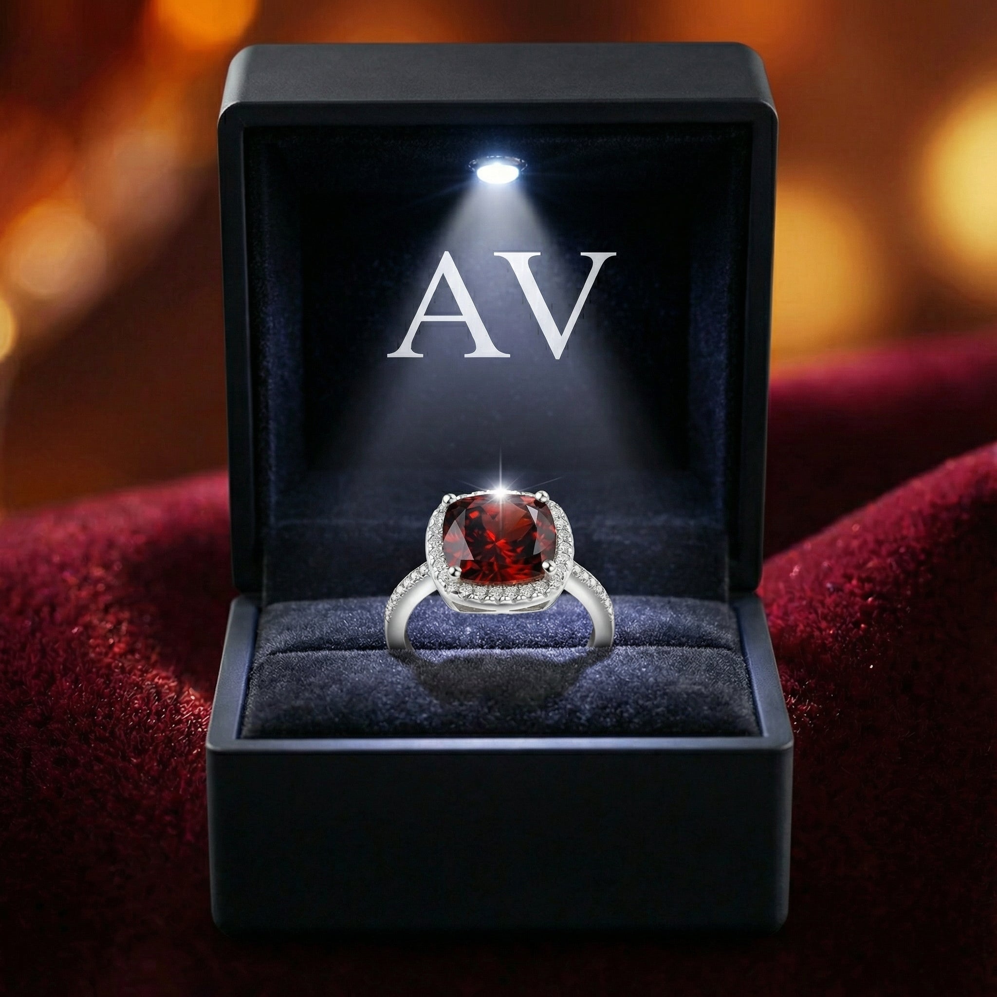 Cushion cut simulated garnet silver ring presented in a black LED-lighted jewelry box.