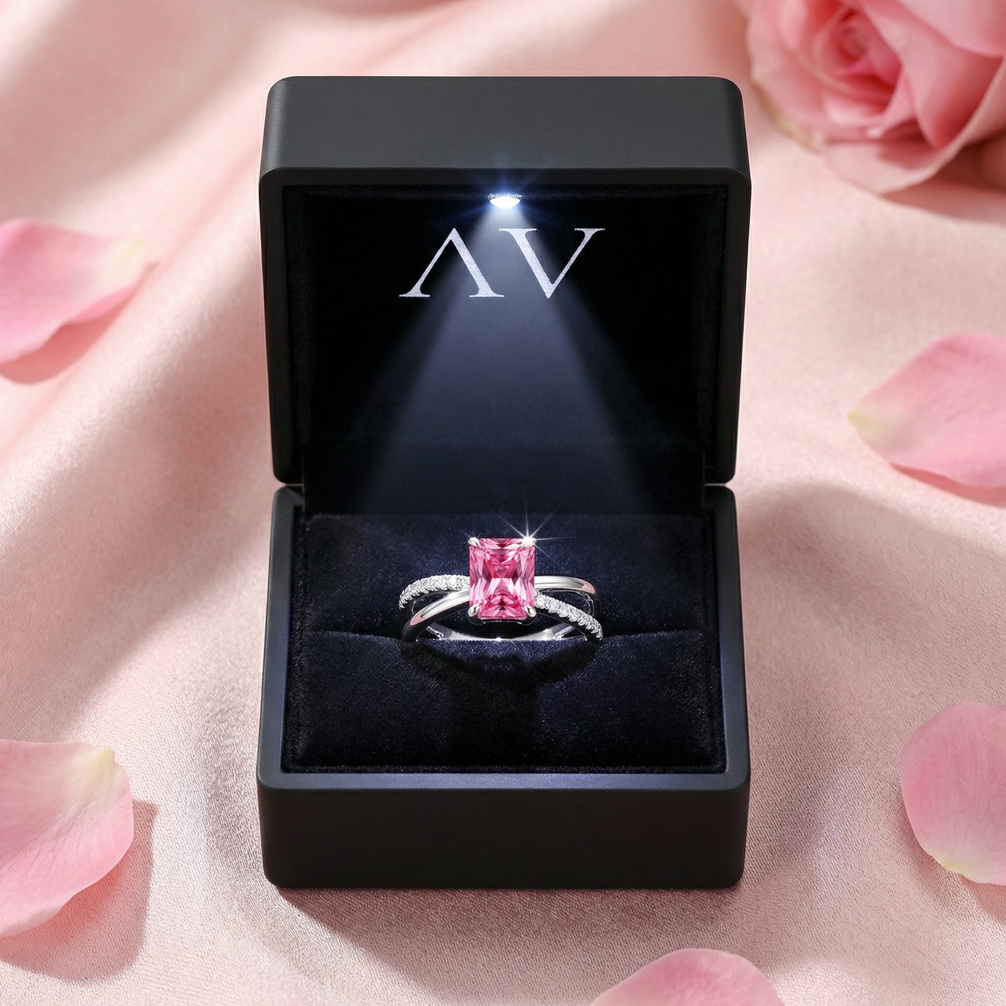 The Elisenne pink tourmaline silver ring displayed in a premium lighted black jewelry box with rose petals.