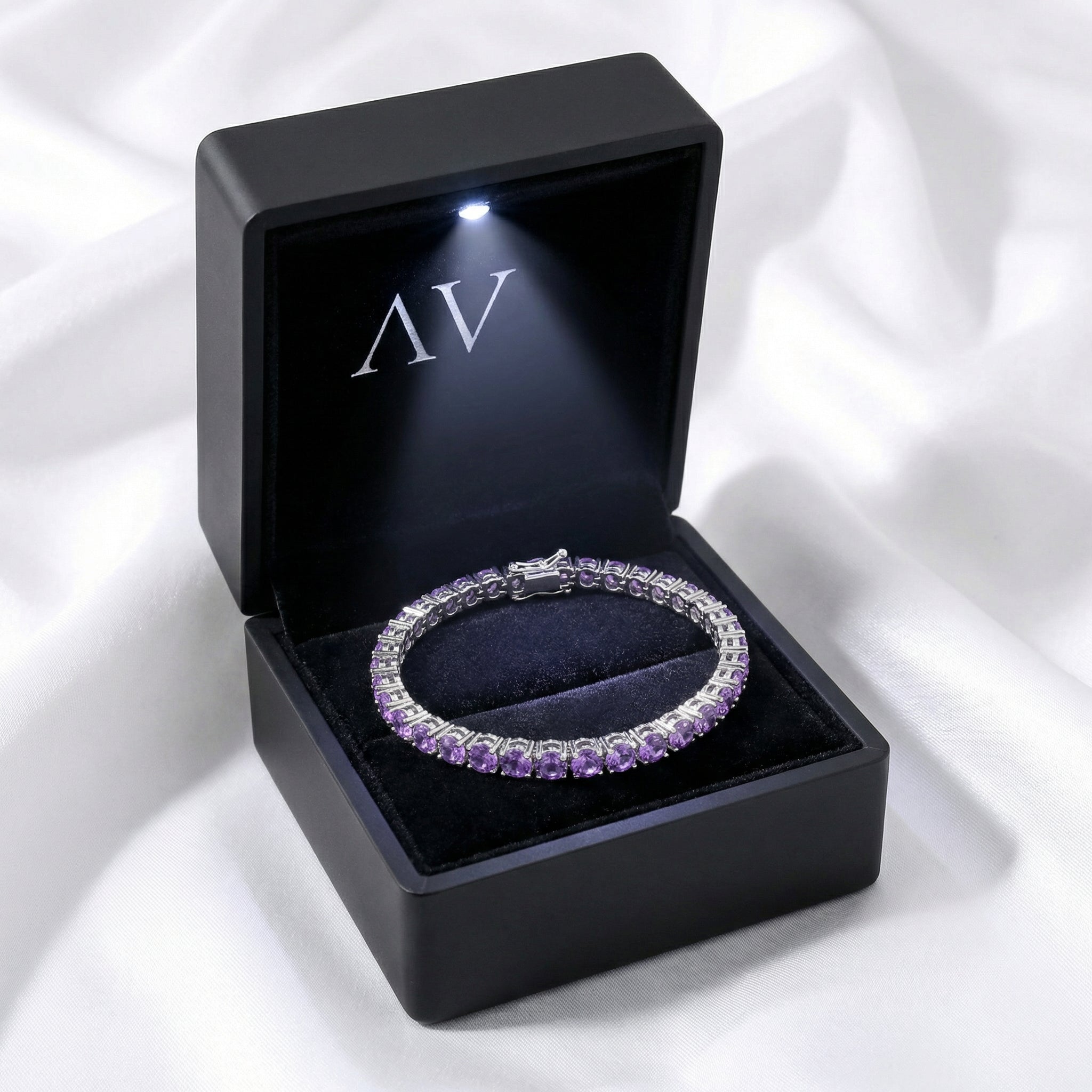 Purple simulated amethyst tennis bracelet in stainless steel inside a black LED-lit jewelry gift box.