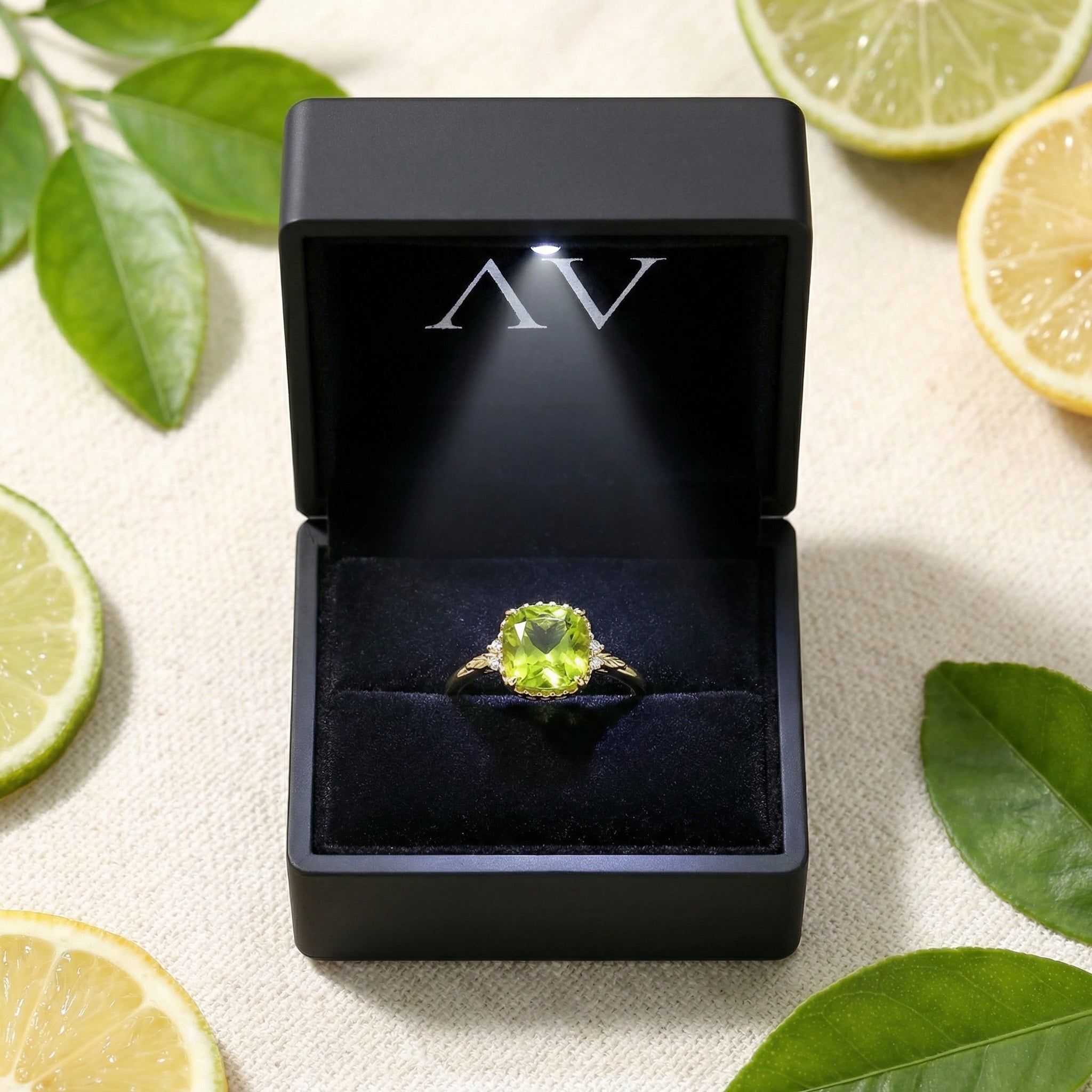 Cushion cut peridot gold vermeil ring in a black lighted jewelry box with citrus props.