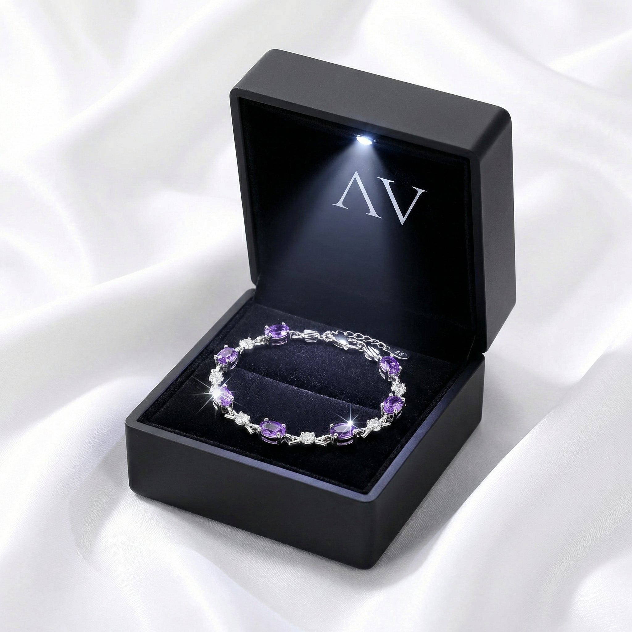 Sterling silver bracelet with oval simulated amethyst stones in a luxury black LED-lit jewelry gift box.