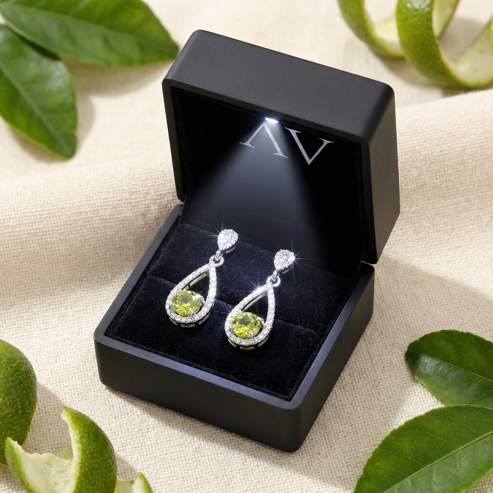 Valerelle sterling silver peridot drop earrings in a black LED-lit presentation box with lifestyle props.