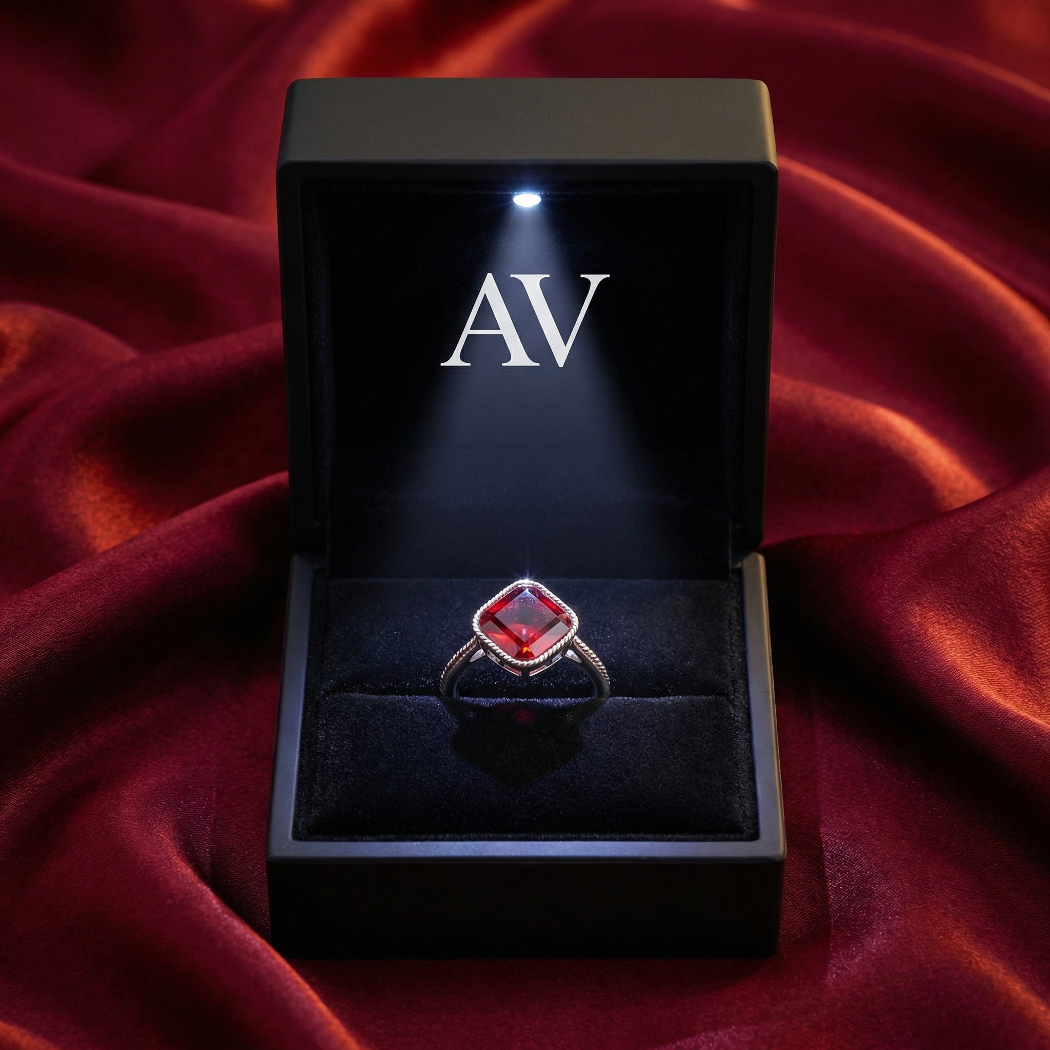 Square-cut simulated ruby sterling silver ring in a black LED-lit gift box on red silk.