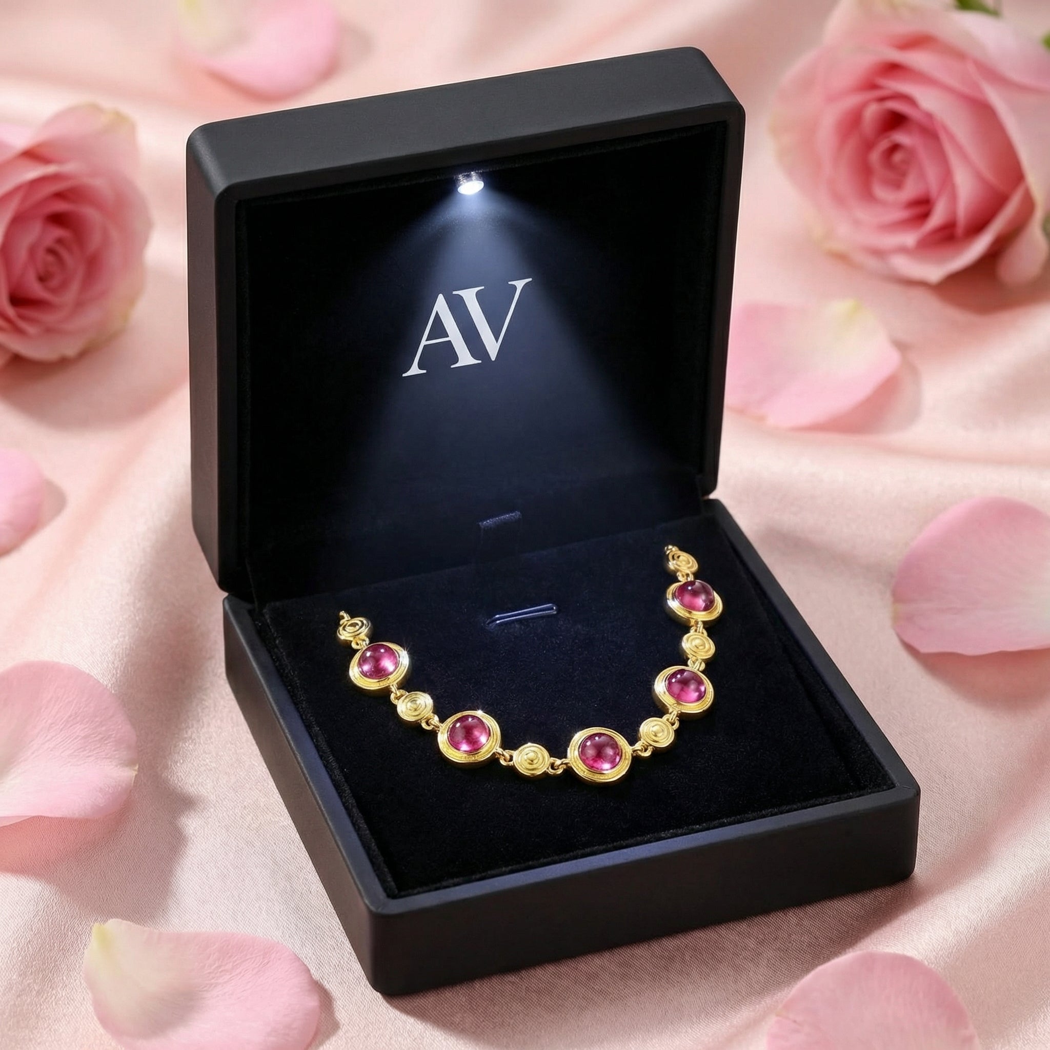 Pink tourmaline station bracelet presented in a black LED-lit jewelry box with rose petals.