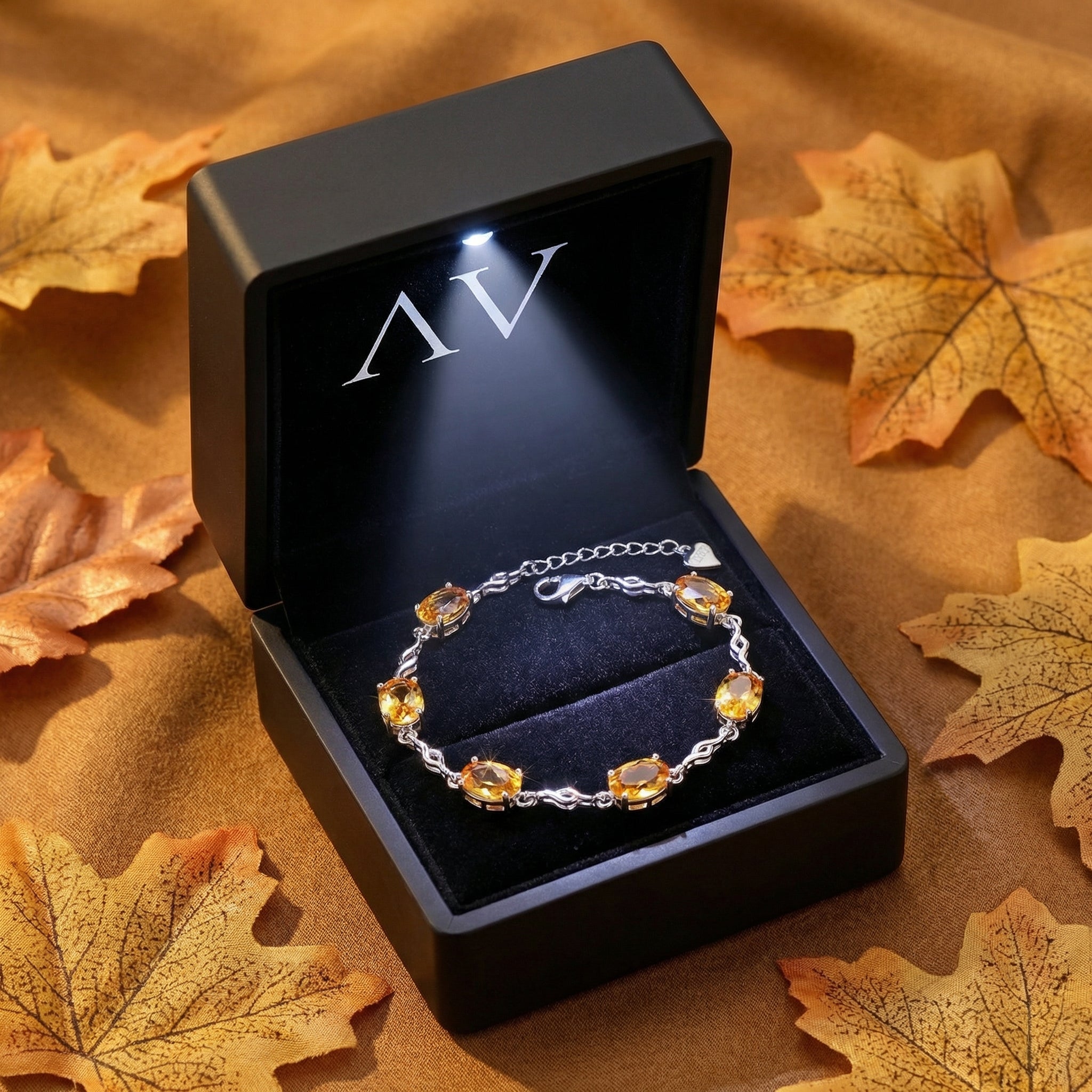 Sterling silver simulated topaz bracelet inside a black LED-lit jewelry box surrounded by autumn leaves.