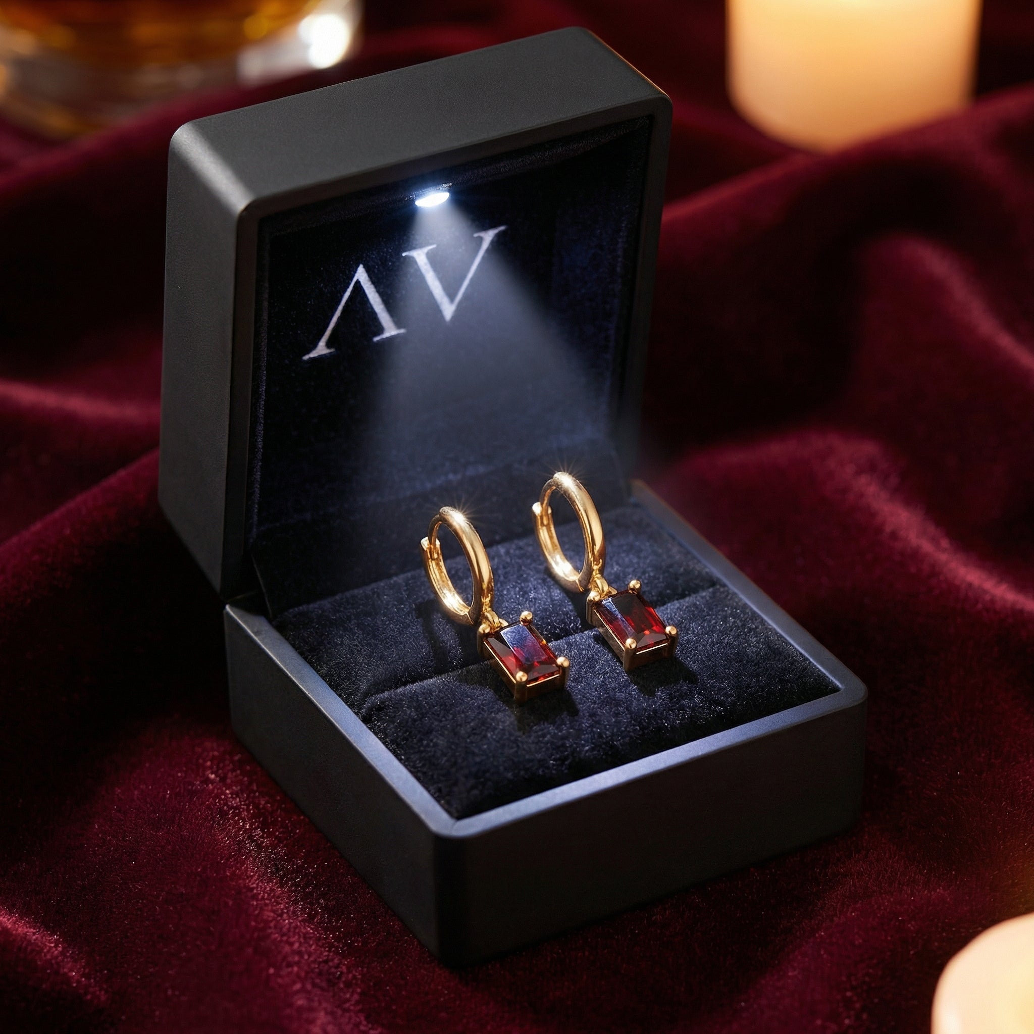 18K gold vermeil emerald-cut simulated garnet earrings displayed in a lighted black jewelry box.