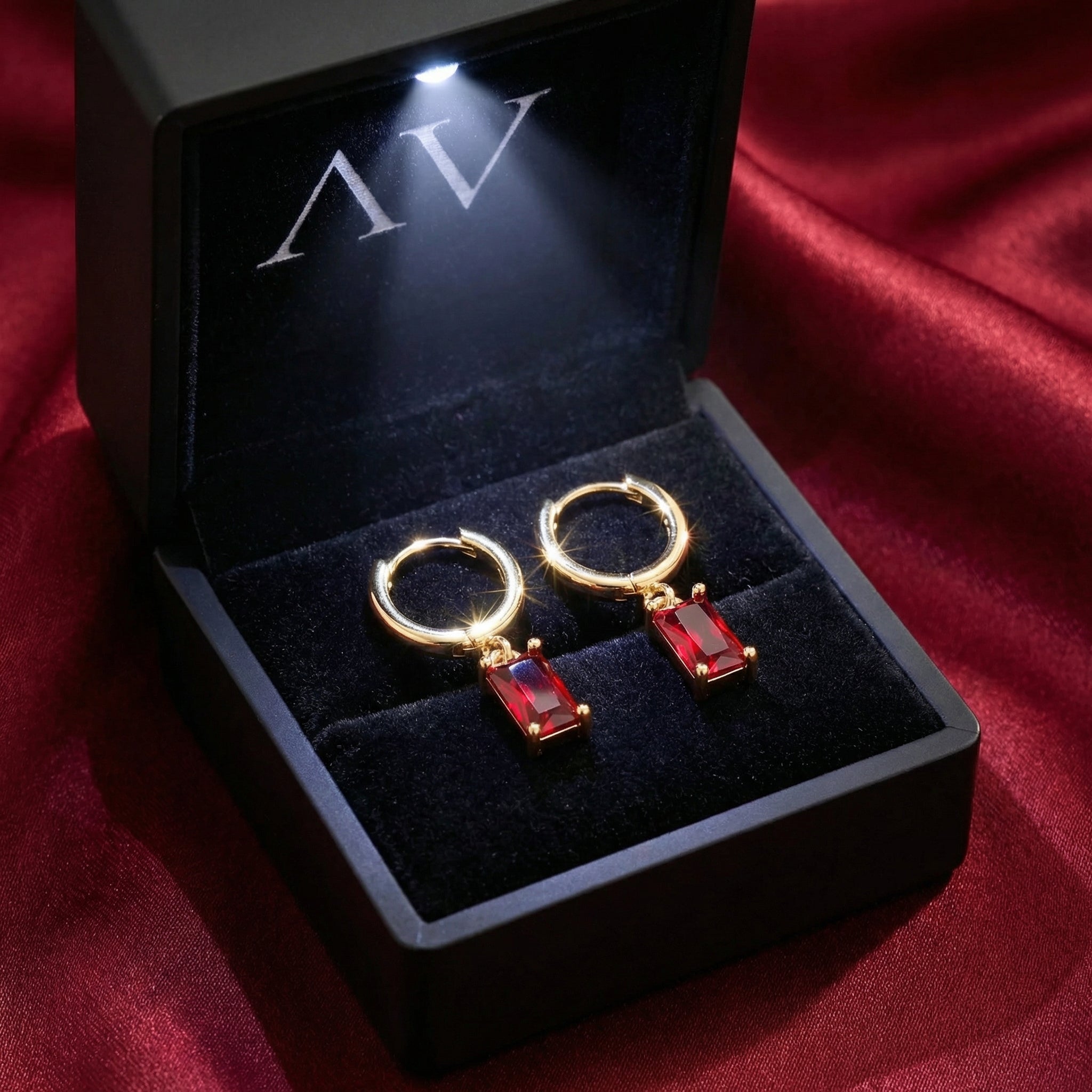 18K gold vermeil simulated ruby drop earrings inside a lighted black jewelry presentation box.