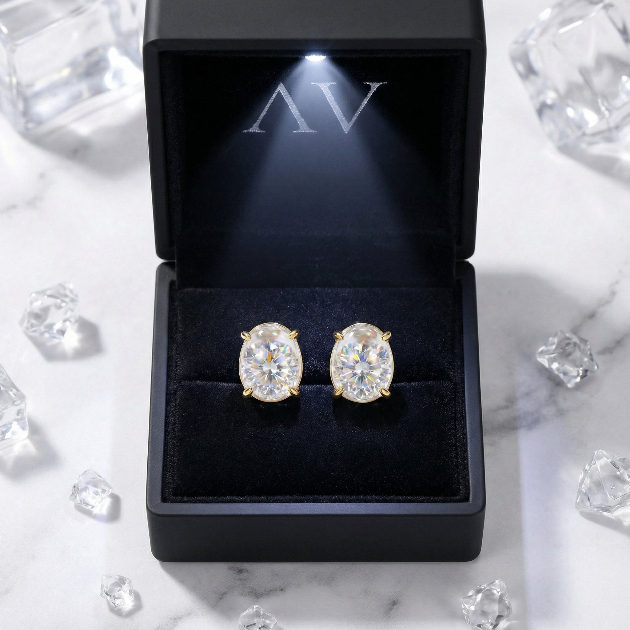 Oval simulated diamond stud earrings in 18K gold vermeil inside a black lighted jewelry gift box.